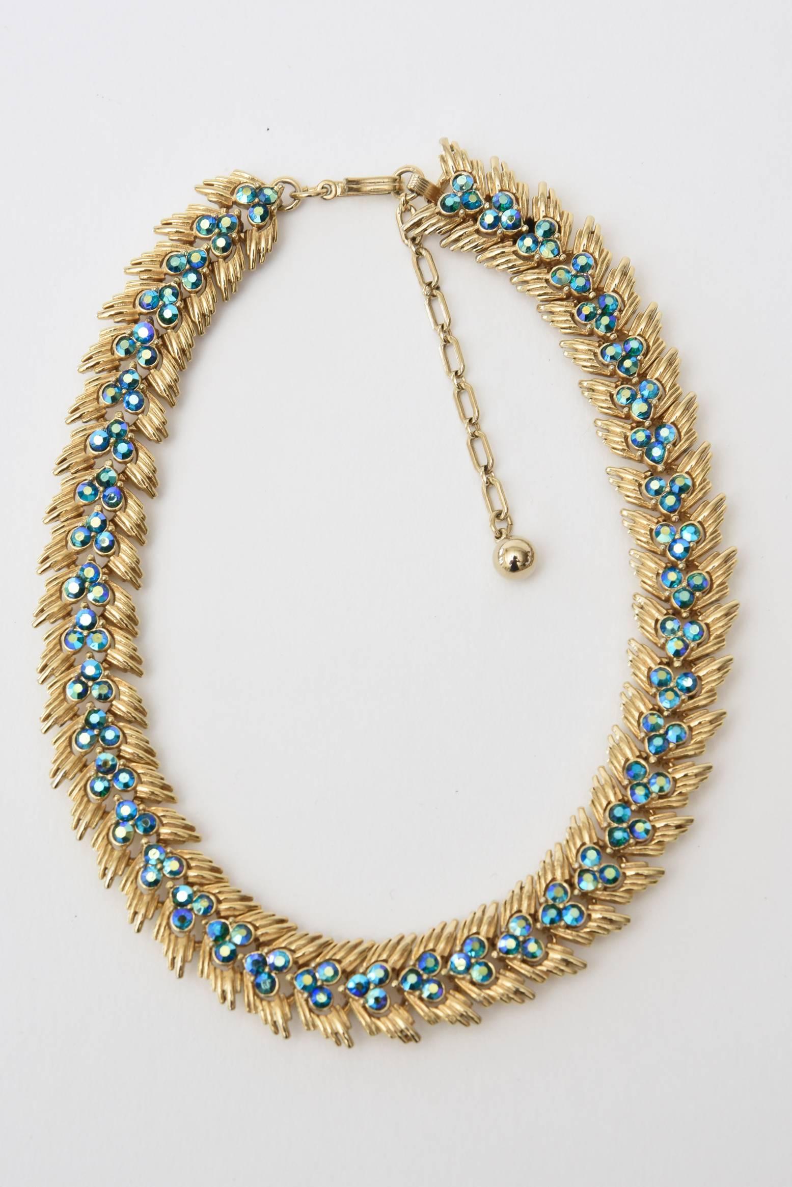 Dieses wunderschön gefertigte Modeschmuckset von Trifari ist aus der Mitte des Jahrhunderts. Es handelt sich um eine Halskette mit passenden Clip-Ohrringen. Er hat eine üppige pfauenartige saphirblaue bis türkisfarbene Farbe. Die Kristallsteine sind