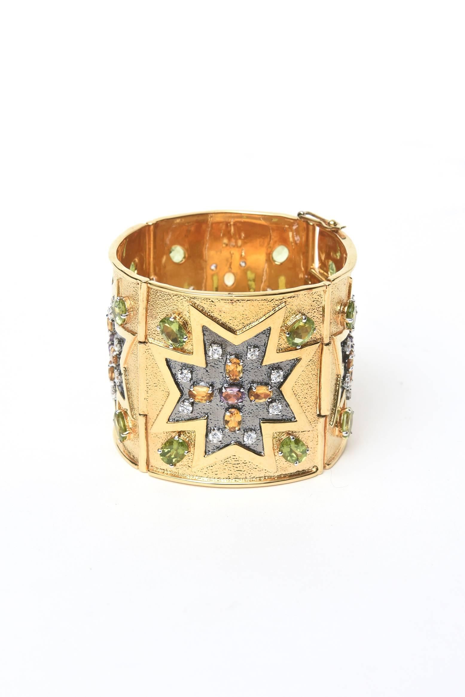 This stunning and dramatic wide cuff bracelet has 4 panels of designs of stones of amethyst, citrine, peridot and rhinestones in a star like formation. It is gold plated over sterling silver. It is most likely one of a kind. The array of colors and