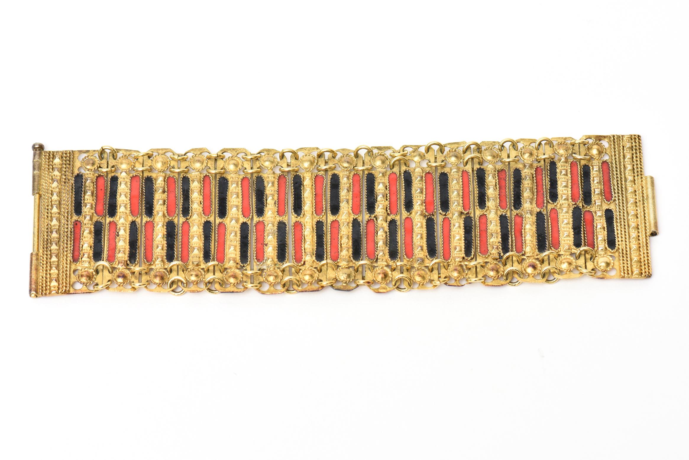 This beautiful vintage Grecian cuff bracelet is a combination of red and black enamel set against gold plated metal with chain and link work. It is from the 50's. It is marked Made In Greece. There is a long pin that closes the bracelet into cuff