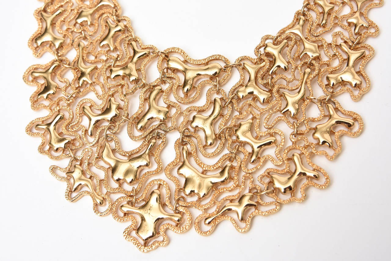 This killer and stunning vintage Monet signed sculptural bib necklace has abstractions of design. The textural outline of forms has high polish gold tone inner forms that connect to each other. So there are 2 different textures; one polished and the
