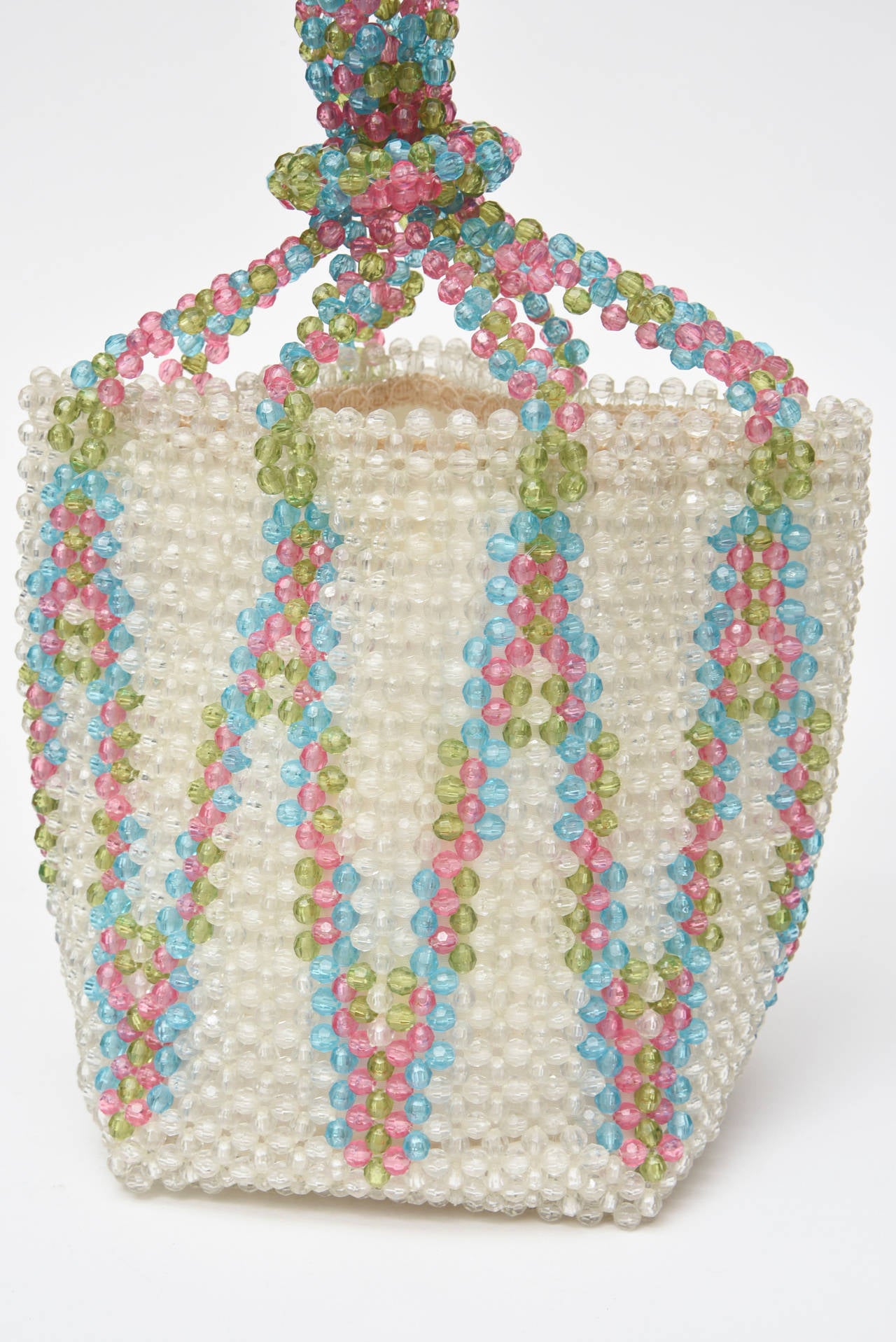 The colors of glorious summer time and resort dreams are abundant in this pink, turquoise and chartreuse chic handbag that is Italian and of the great work of Coppola e Toppo. It consists of plastic beads of a graphic design set against a white