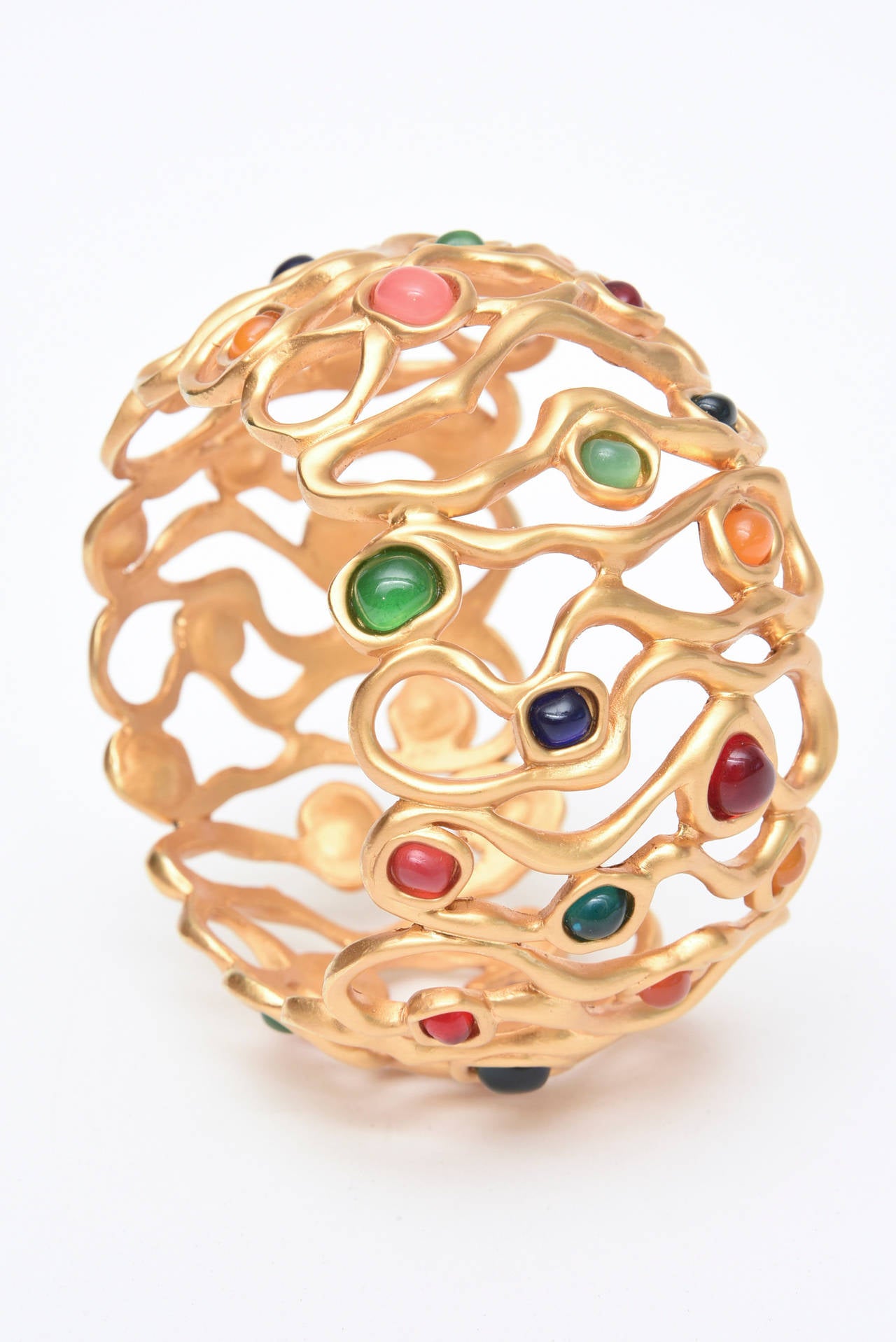 The open sculptural design of the gold plated wide cuff bracelet with amazing The luscious jewel tone colored stones large cuff make this a statement piece. It has a very Yves St Laurent look to it!  It is like the tree of life in circular form. The