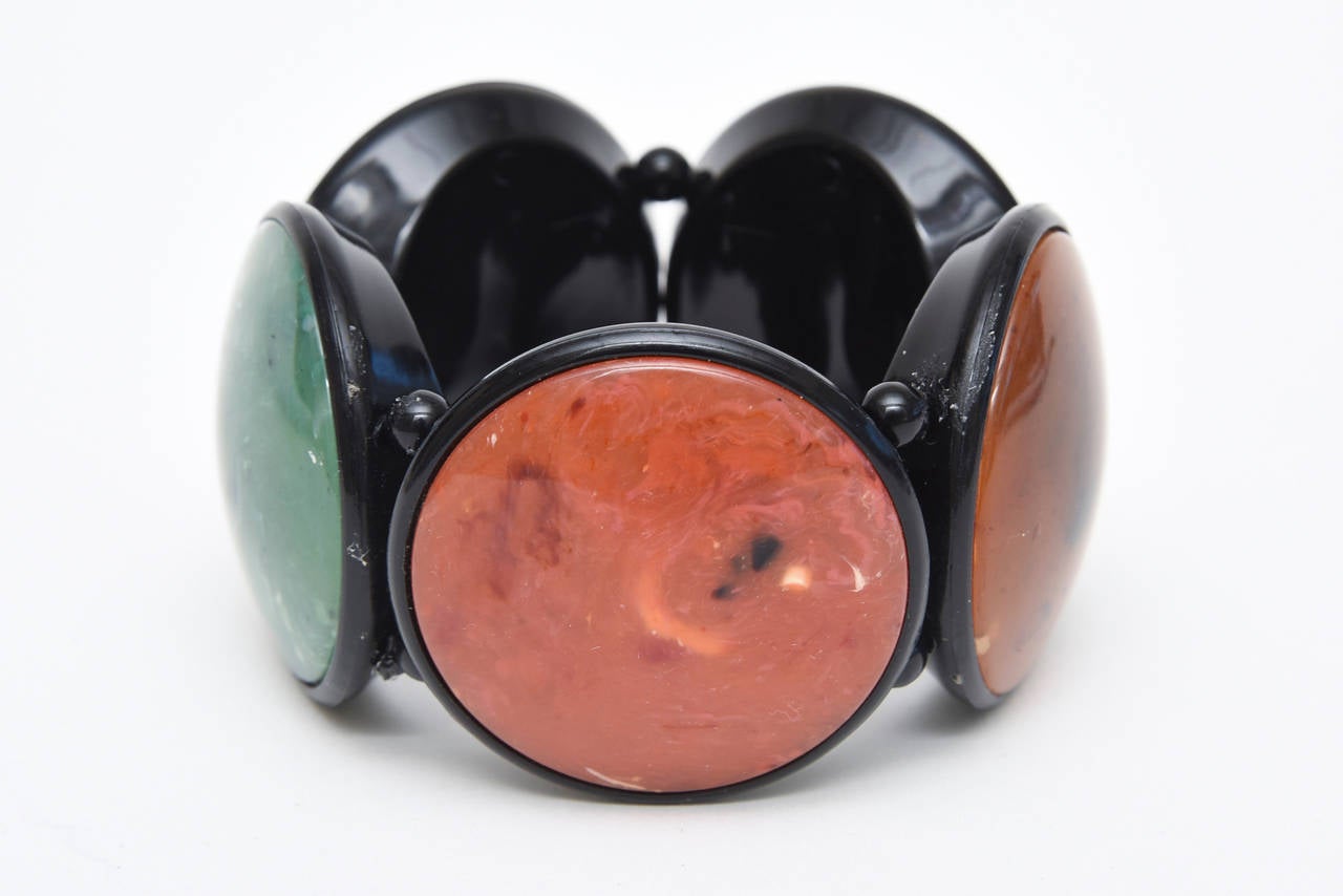 This great, dramatic vintage French resin disk bracelet has 5 disks in gorgeous various colors that look like stone. The colors are pink, mustard amber yellow, sage green, rust orange, etc. It is a from the 80's and a elastic stretch bracelet. It is
