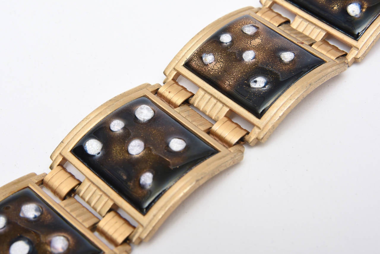 White enamel dots overlay the brown enamel in this vintage cuff form bracelet. It is gold plated metal with enamel and presents a graphic quality to it. Lovely on the wrist. Once fastened it becomes a cuff form bracelet. This is mid century modern