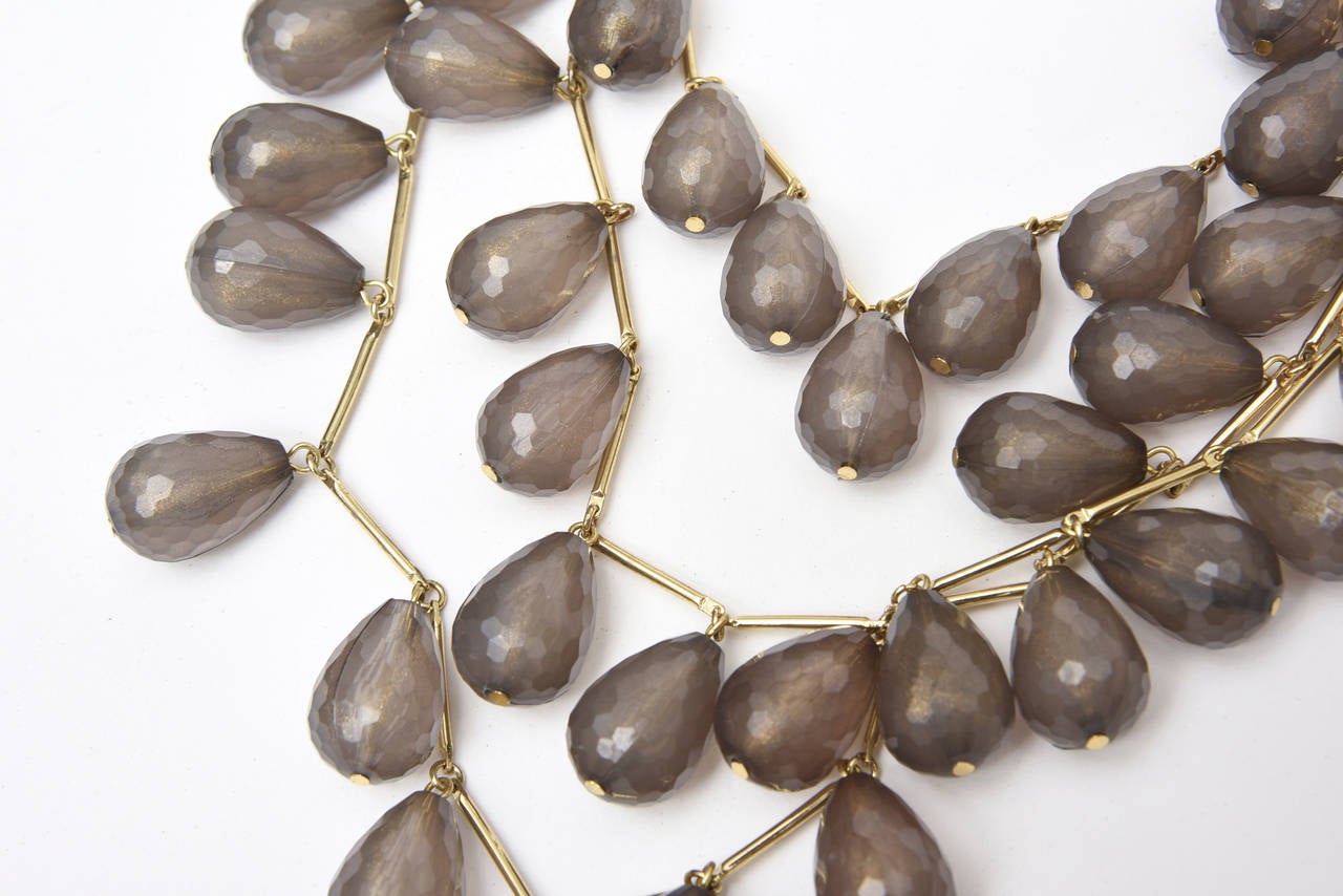 Three strands of gilt metal and gray resin coffee bean shaped beads make up this lovely and arresting vintage necklace. They are like almond shaped resin drops on a chain. It has a great presence and lays well on the neck and chest. It looks