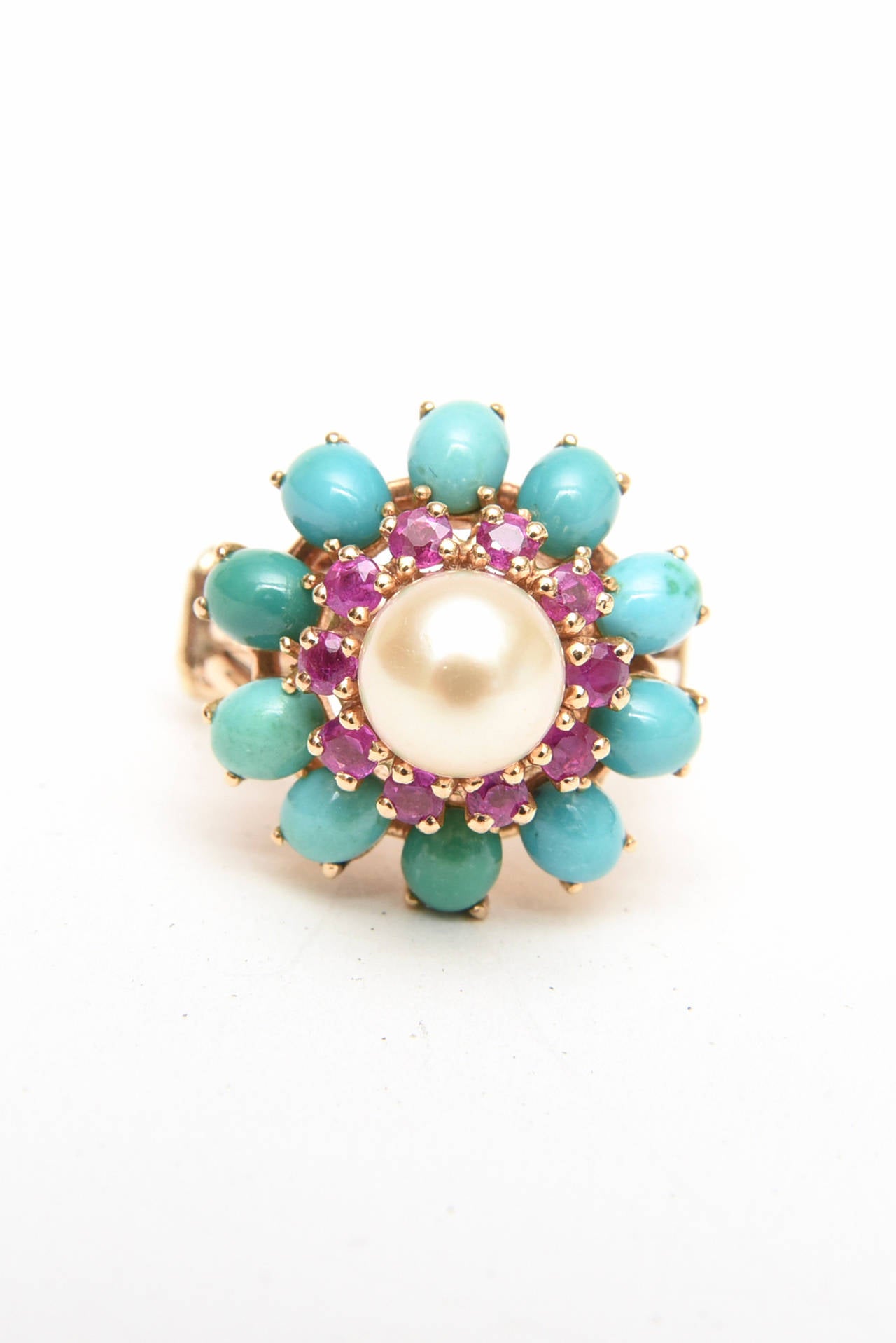 This lovely dome vintage cocktail ring Is 14 Karat yellow gold with bands of rubies and turquoise surrounding the pearl.  It has 10 oval cabachon cut turquoise stones that are beautifully prong set. The ruby stones preceed these and there are 10 of