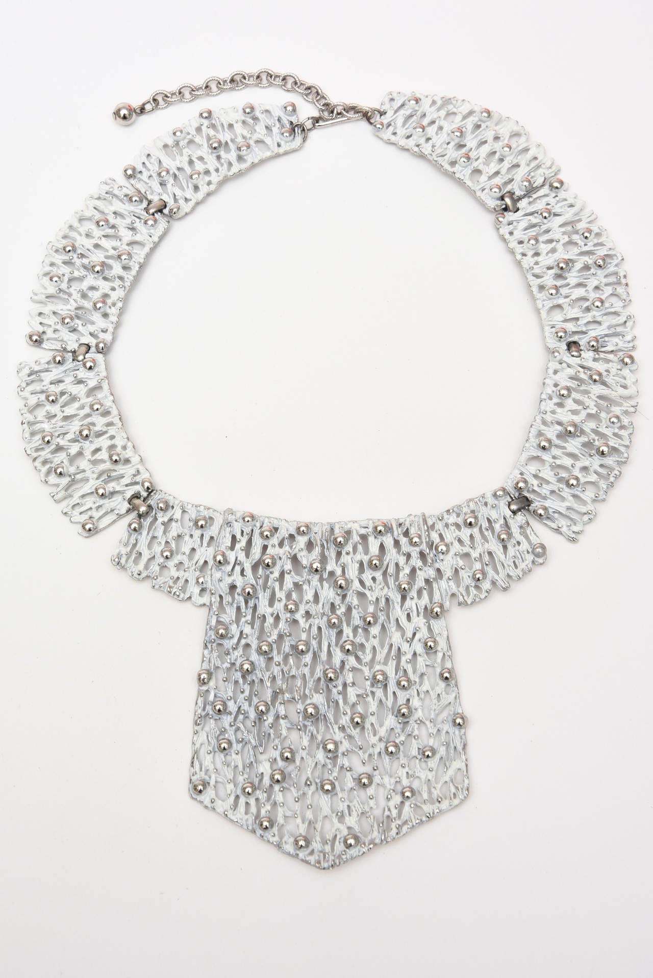 Looks like clusters of ice encased in texture and molten white metal in this Napier hard to find set of a collar necklace and matching clip on earrings.
There are tiny chrome plated balls randomly placed all over the necklace and earrings.
A show