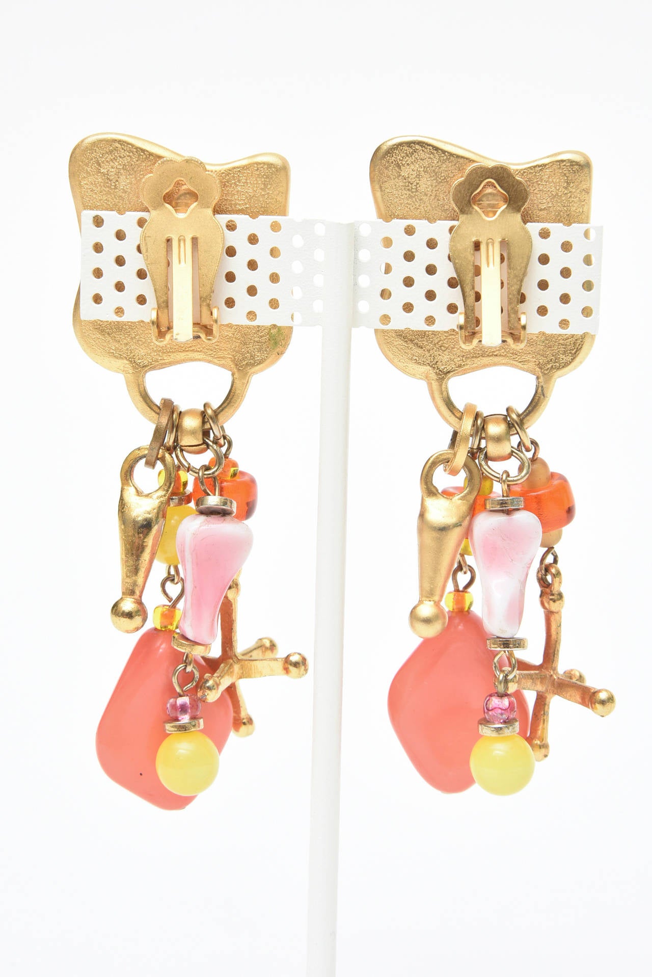The luscious colors of coral, orange, pink and yellow of these playful and happy earrings are set against gold tone. Call them beach, resort, poolside or St. Barths.. They are signed on the back by Robert Rose and are clip on earrings.
The dangling