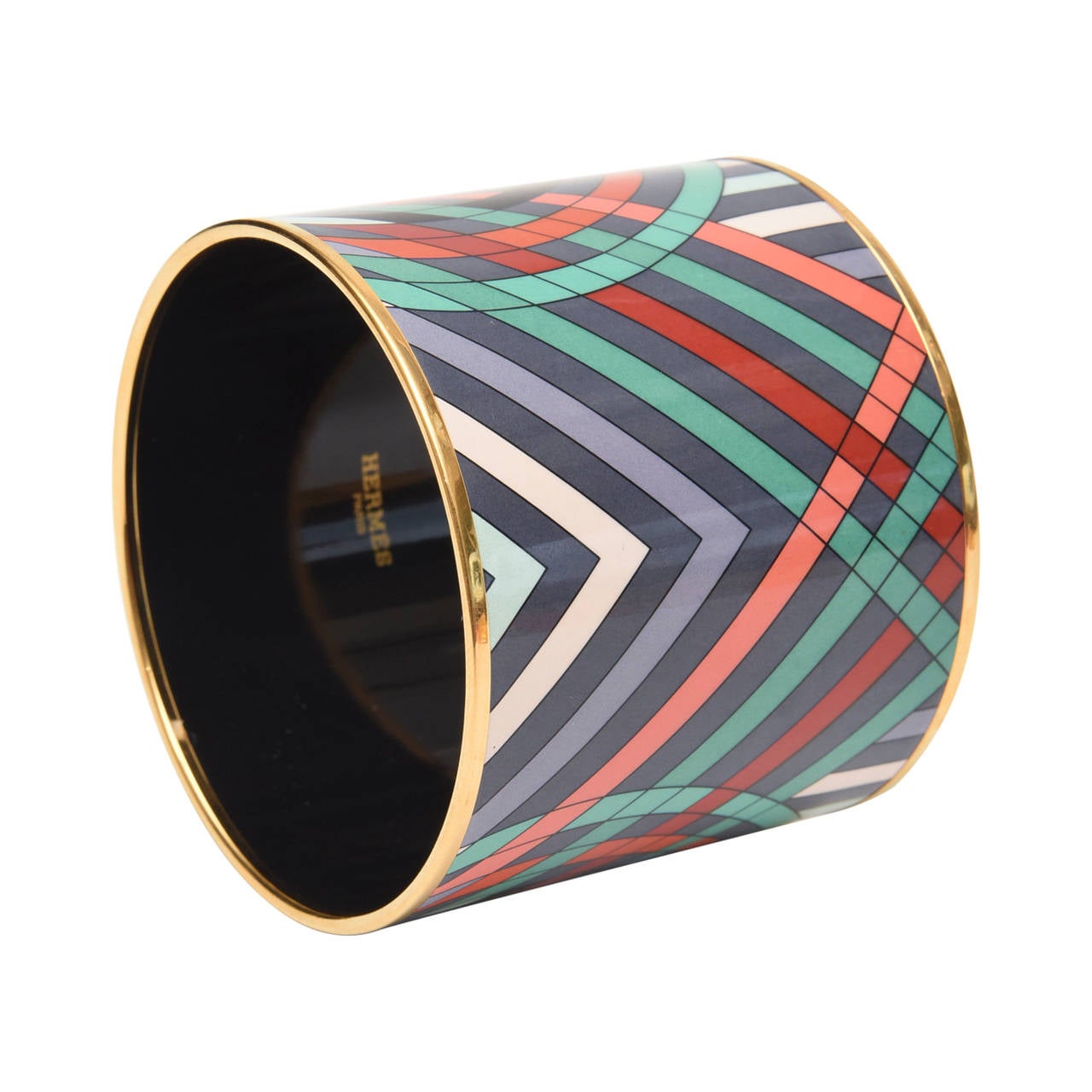 In this fabulous Hermes wide cuff bracelet, the great play of colors of orange, black, gray, tan, white and green are in a moving optical geometric form. It is signed Hermes, Paris on the interior of the black enamel.
On either side is trimmed in a