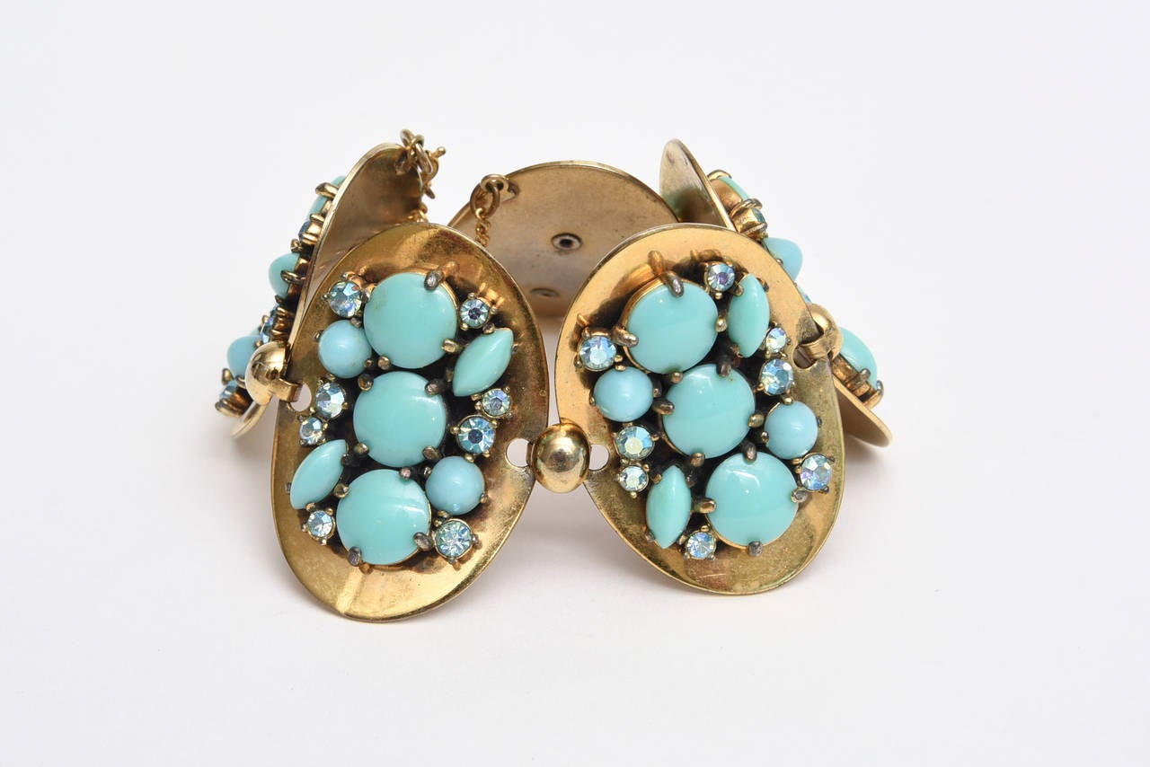 Ce magnifique bracelet vintage d'Elsa Schiaparelli est composé de 5 disques ovales reliés entre eux et de grappes de fausses turquoises et de strass sur fond de laiton doré. Il y a une chaîne de sécurité dessus. Ce joli bracelet se porte en journée