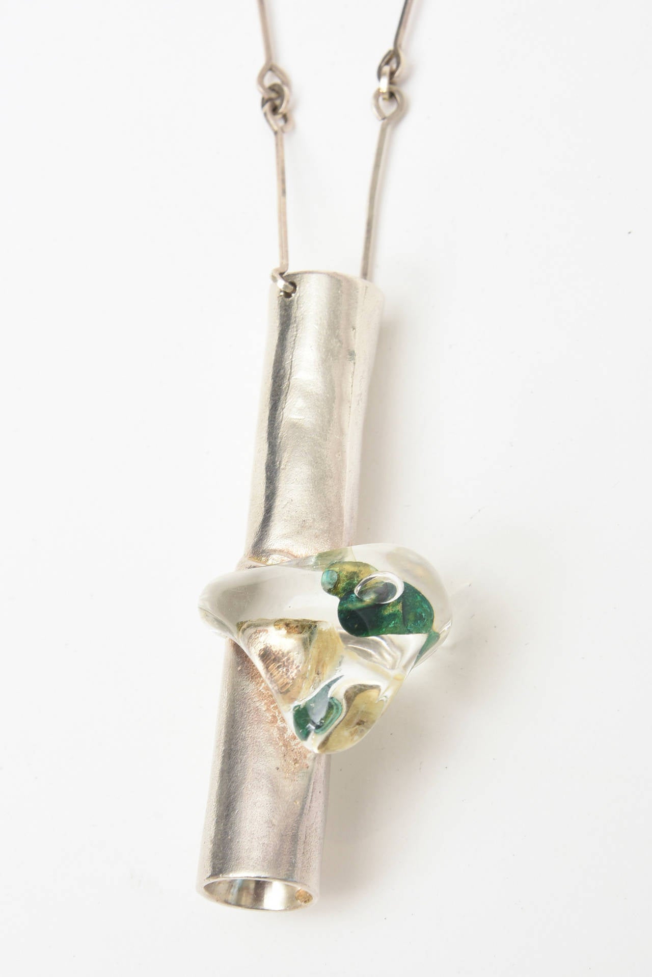 This stellar and sculptural vintage long necklace has a sculptural sterling silver tube with a chunk of green resin embedded in the sterling. Marked. Hallmark 925 Finland Lapponia. Bjorn Weckstrom designed this piece of art and sculpture and jewelry