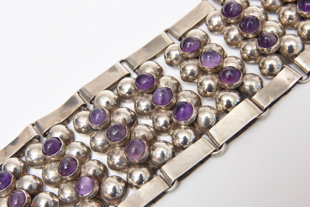 This hand wrought gorgeous and early vintage Mexican hallmarked cuff bracelet of sterling silver and amethyst are comprised of 10 rows of 8 dome like sterling silver balls with 3 set amethyst stones on top. it gives it almost an abacus like look.
