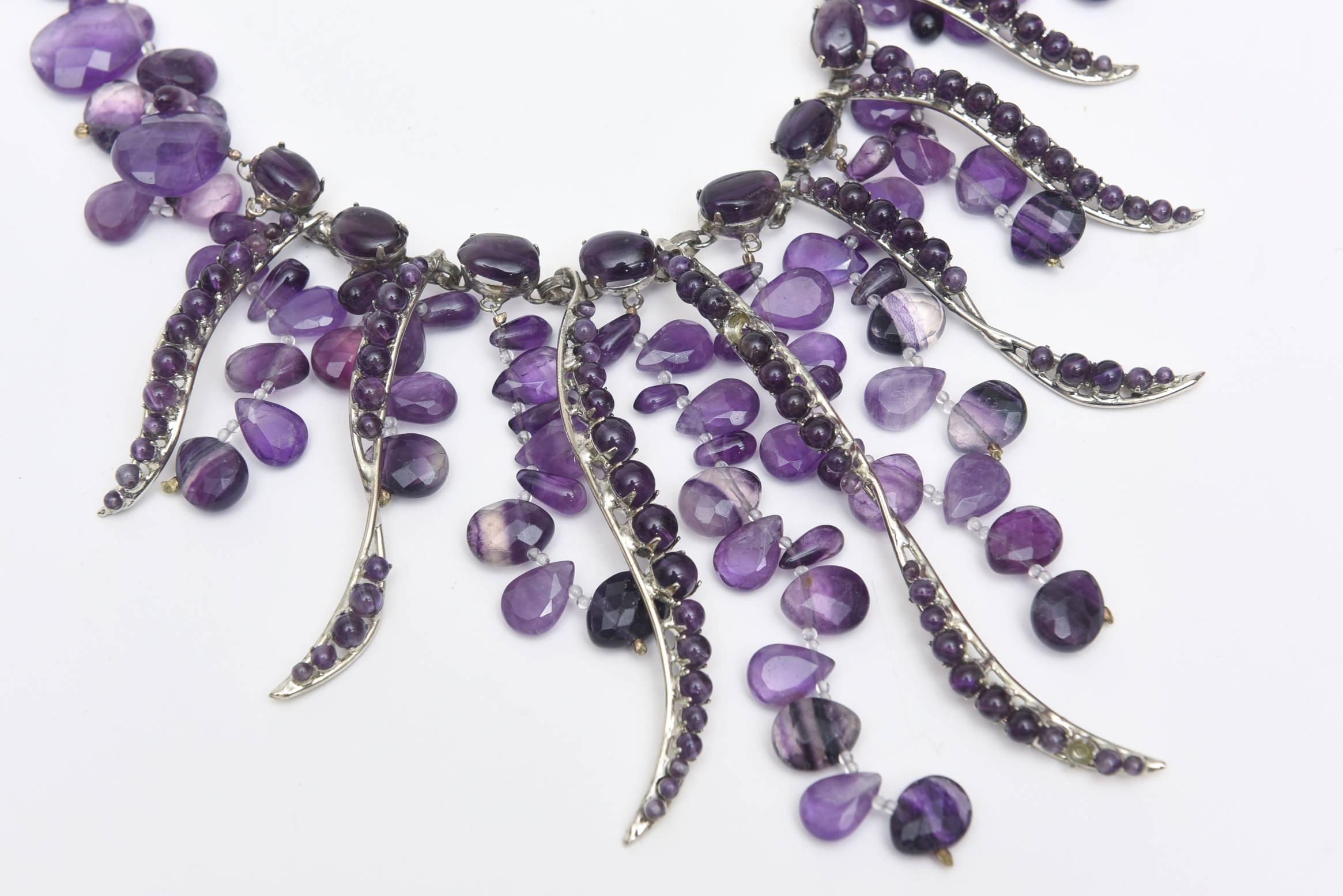 This dramatic and theatrical cascading amethyst and silver bib necklace looks stunning on. It is signed by Siman Tu. His work is in the category of jewelry designer Iranj Monji. SIman Tu is a NYC based well known semi precious stone jewelry designer
