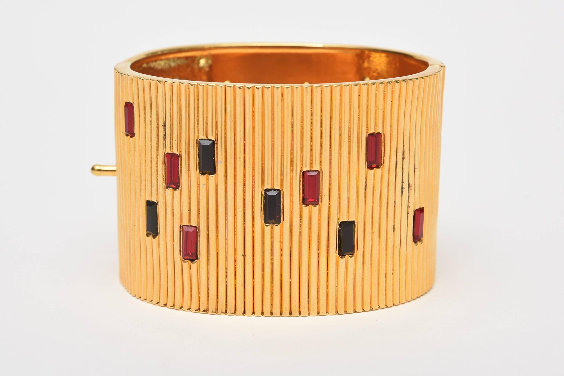 This wide-ribbed cuff gold toned Bracelet, with red and black glass inserts is by Paloma Picasso.  On the tag on the inside, it is written, 