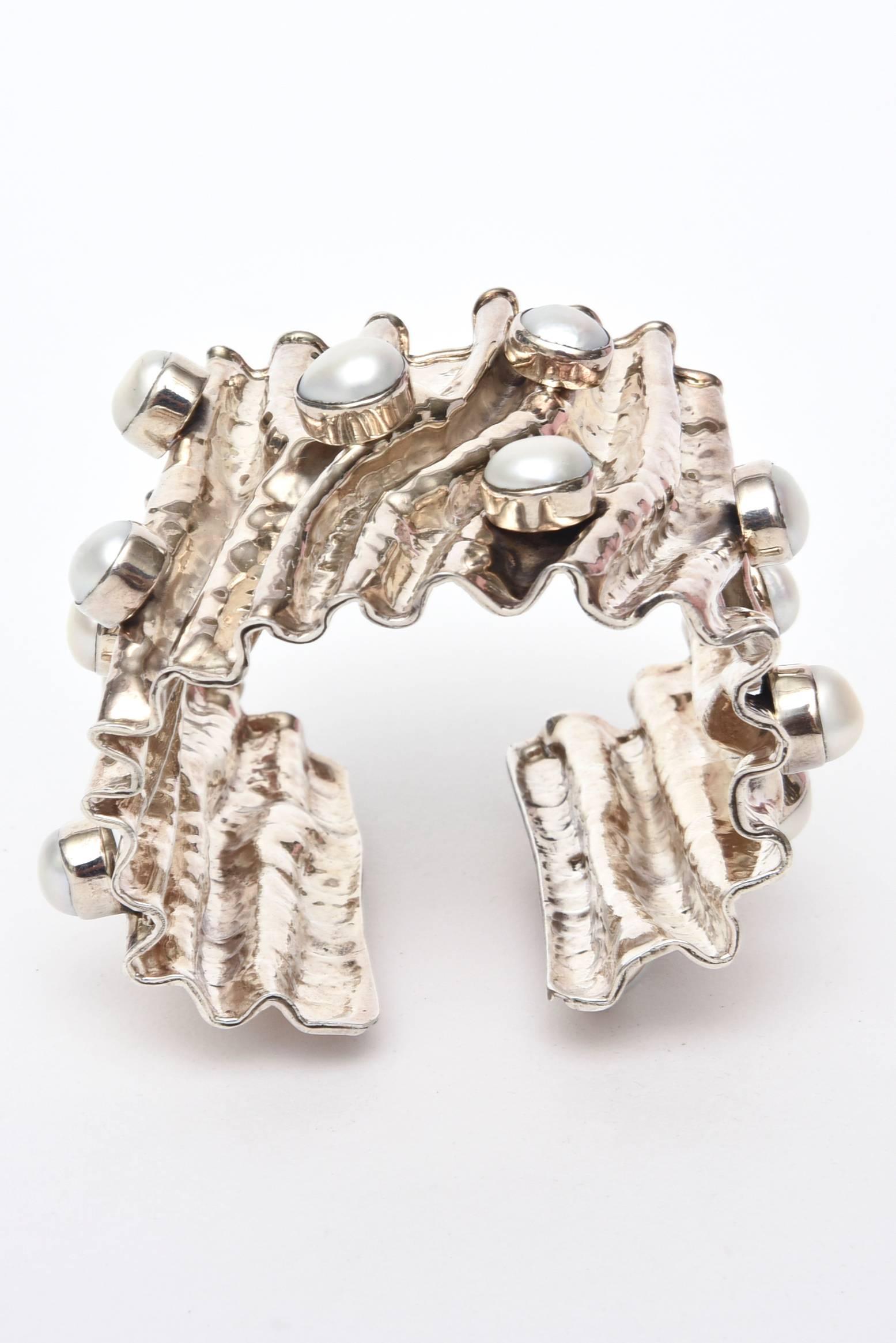 This stunning and sculptural hand wrought sterling silver cuff bracelet has 15 real pearls set in a protruding form, and the silver looks like it has been folded and creased. It has good weight to it. It is marked 