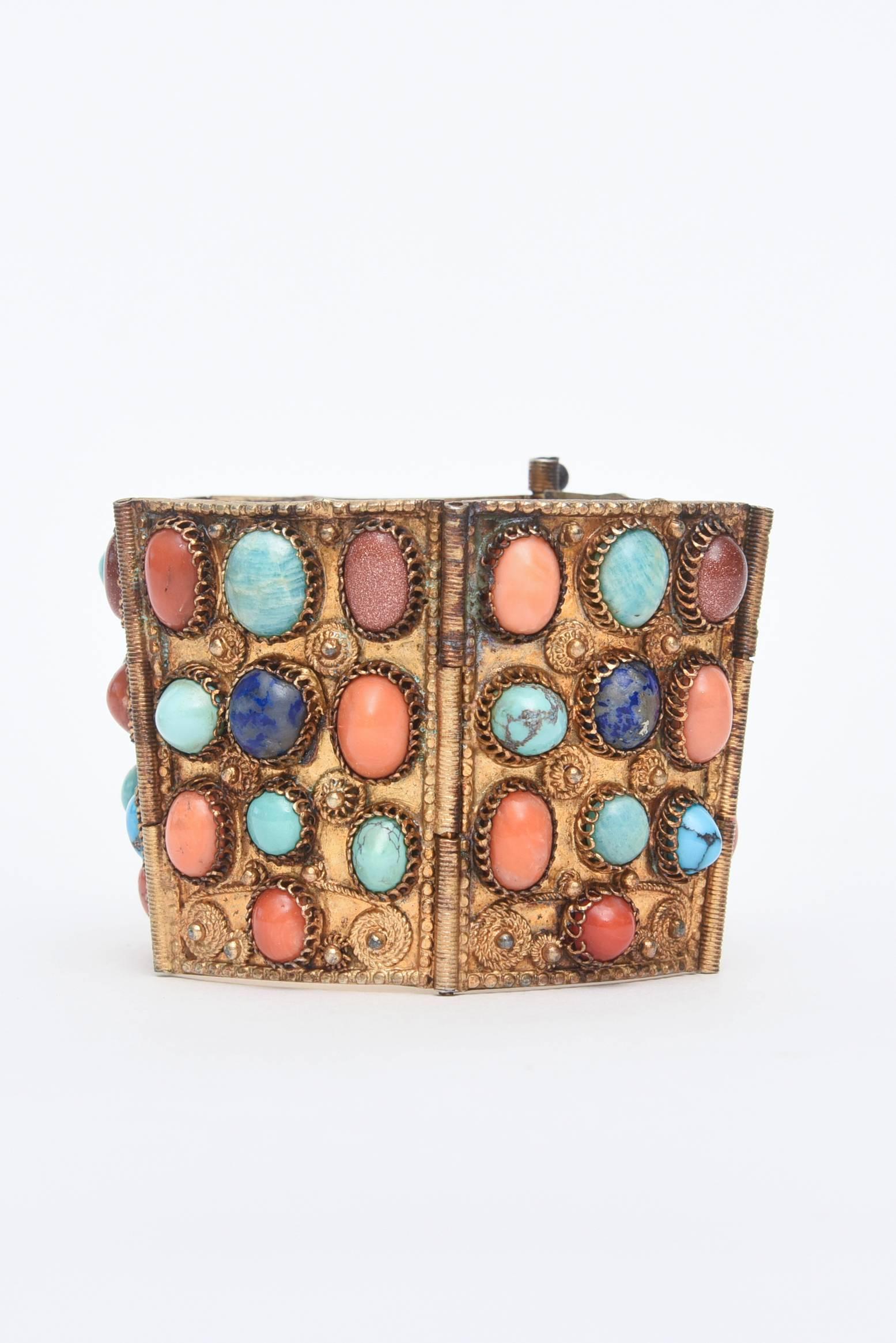 This dramatic and gorgeous cuff bracelet has Egyptian Revival meets Byzantine influences. It is period from the late 30's and has real stones of different coral, turquoise, lapis and Chinese sand stone. It is set against vermeil and has a beautiful
