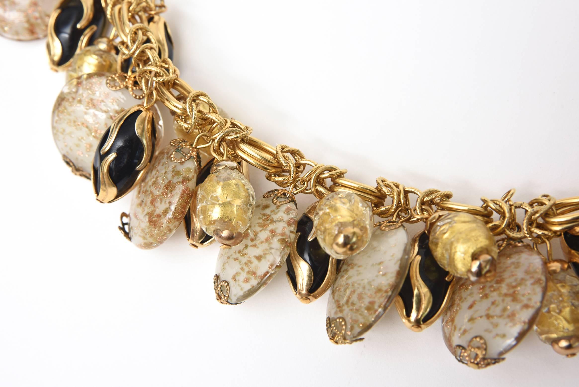 This beautiful and well executed Italian signed Assunta Giovanno dangle charm bracelet is made of  9 round disks of Murano glass with gold aventurine interspersed with black drops of resin and gold resin with gold plated applied swirls. Her work are