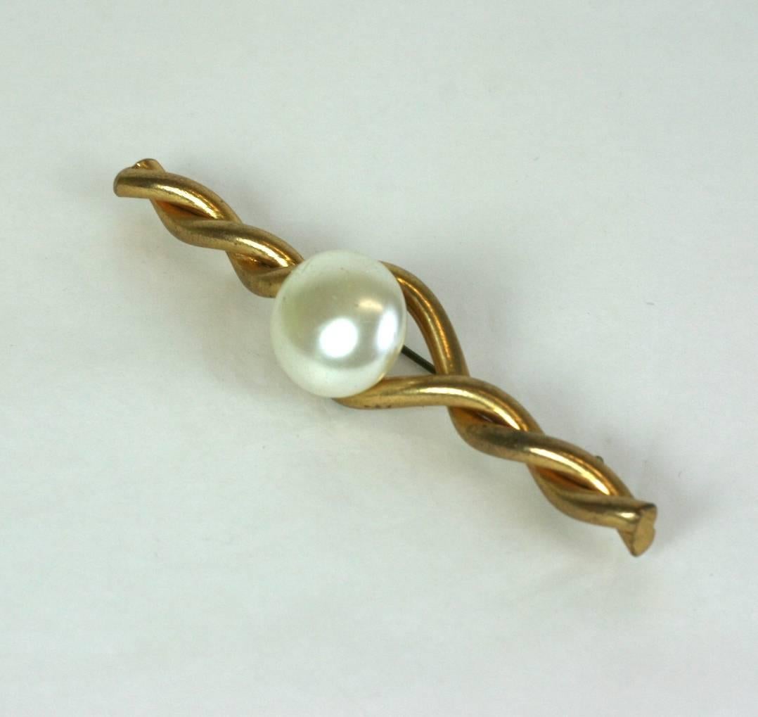 Coco Chanel classic pearl and gilt bronze twist bar pin by Robert Goossens for Chanel.
Composed of a twisted gilt wire with a faux pearl cabochon. Chanel has been photographed often in variants of this brooch. Simply iconic and timeless like its