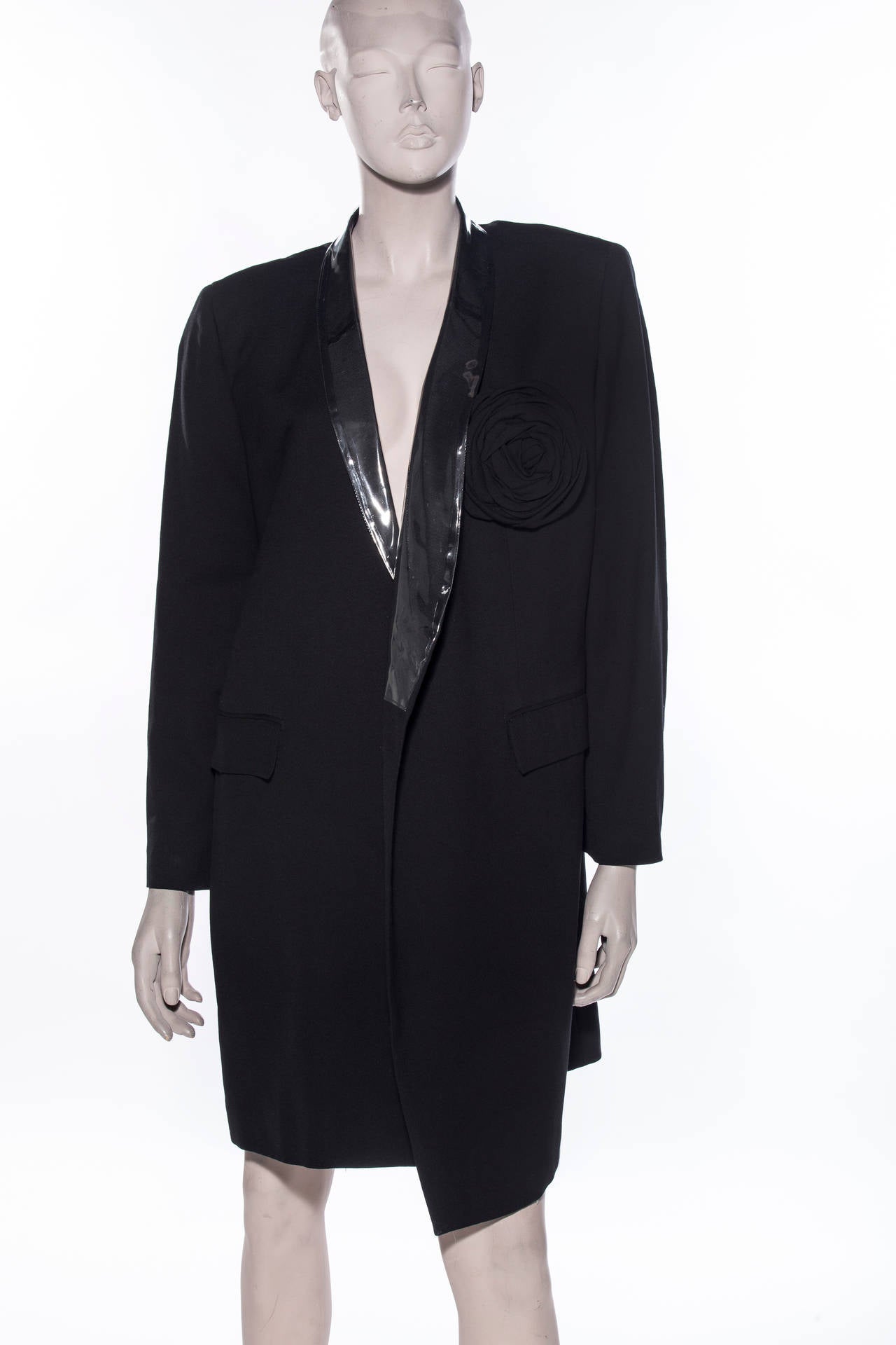 Comme des Garçons, circa 1991, black wool blazer with PVC lapel, rosette detail, dual flap pockets at sides and single button closure.

Bust 32”, Waist 30”, Shoulder 17”, Length 36”