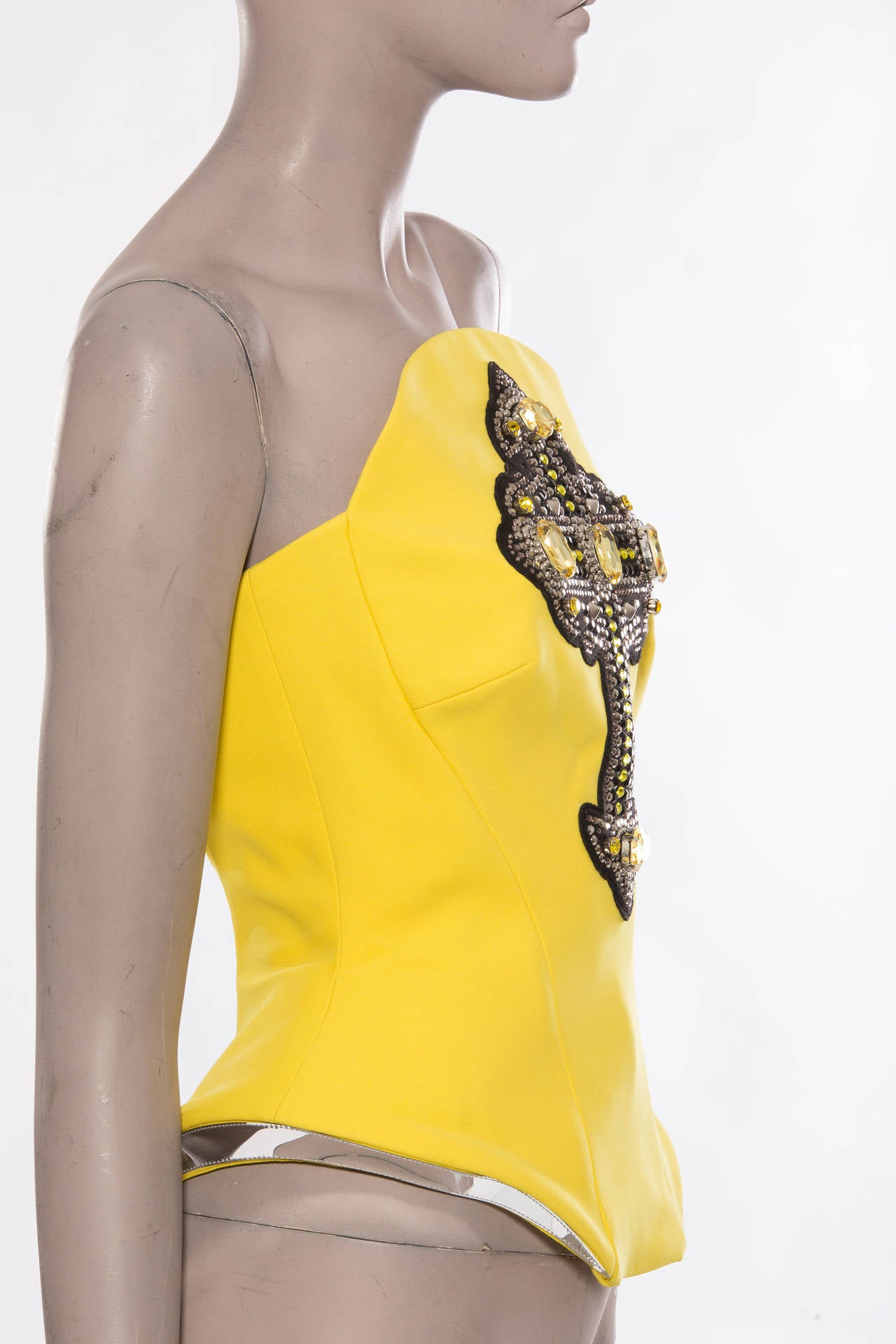 Versace, Autumn-Winter 2012, yellow silk structured bustier, gothic cross appliquéd with multicolor prong set Swarovski crystal embellishment, silver metallic PVC trim and concealed back zip. Includes tags.

Bust 32