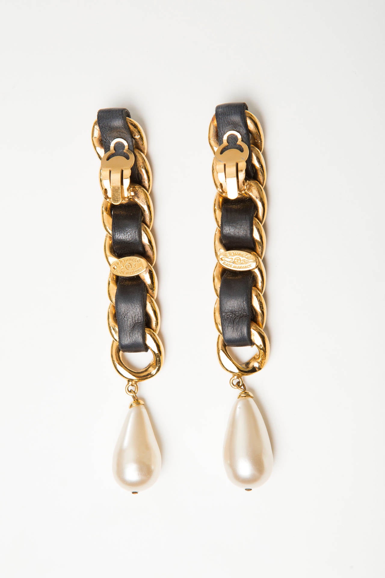 Chanel, Circa 1980s chain drop earrings with black leather trim, faux pearl and clip-on closure. Includes box.  Drop 4.5”, Width 0.63”
