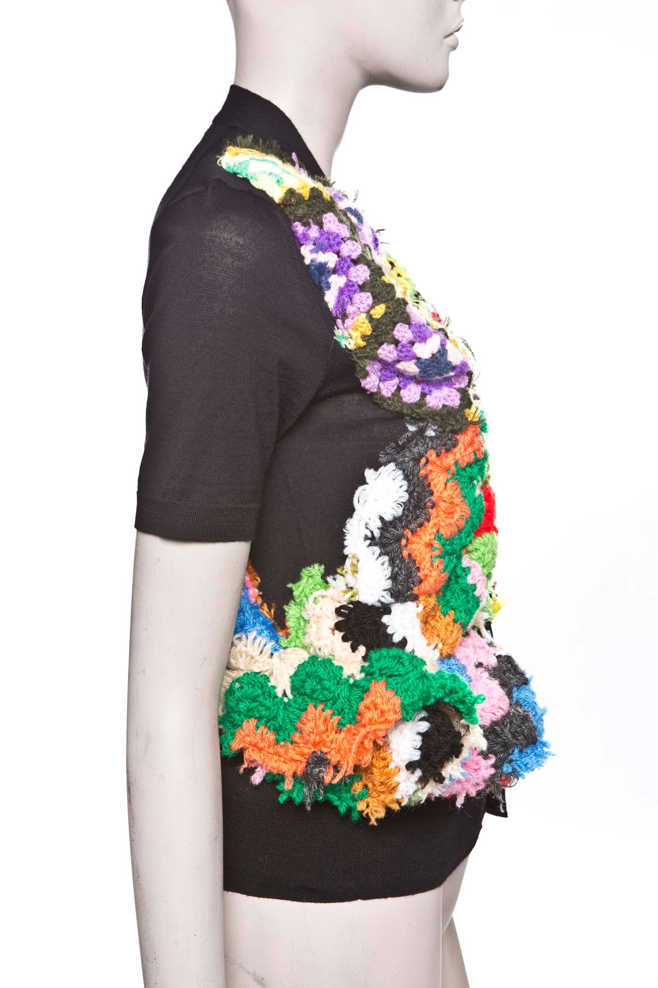 Comme des Garçons, circa 2009 black, wool, short sleeve V-neck sweater with multicolor crochet design and front button closures.

 Bust 30”, Waist 28”, Length 21”