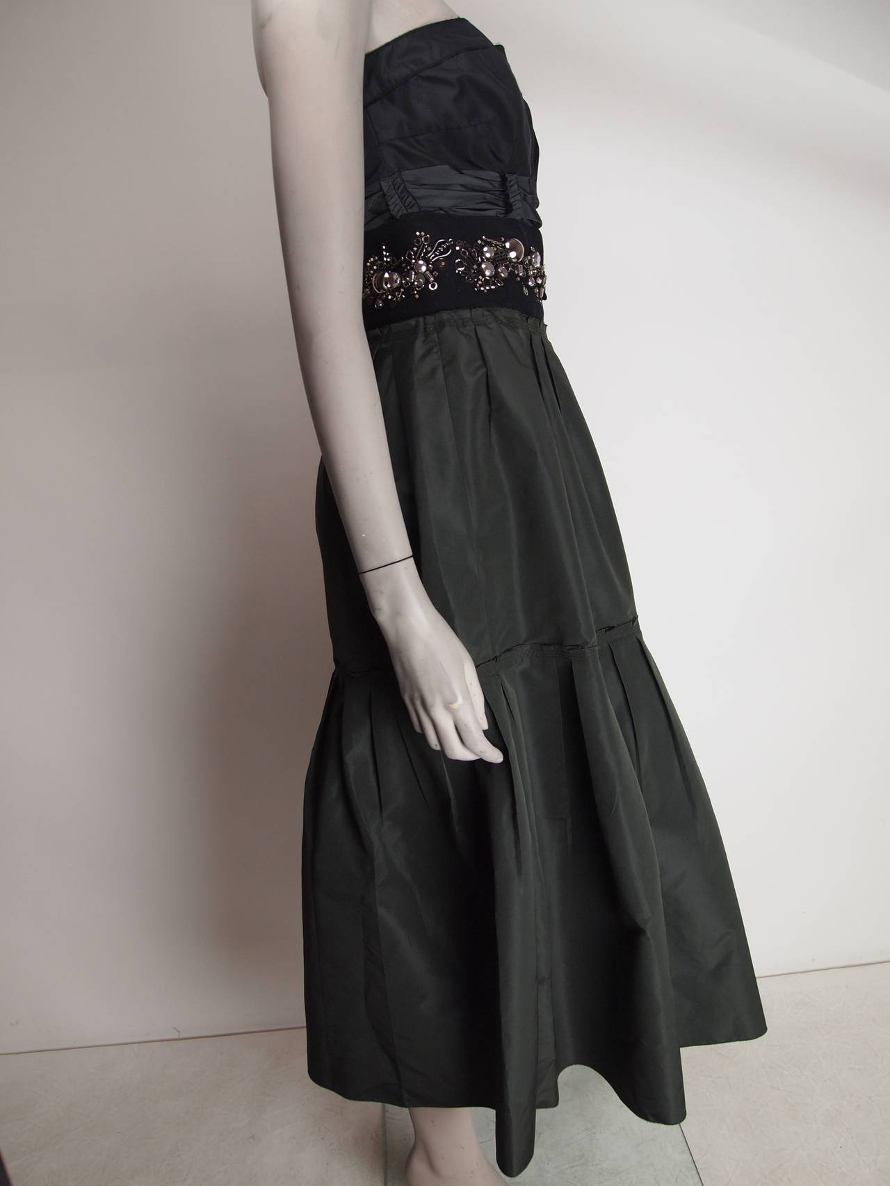 Prada Fall 2006, black and dark green staples dress with silver-tone embellishment at waistband and side zip closure.
Bust 34”, Waist 28”, Hip 38”, Length 45”
