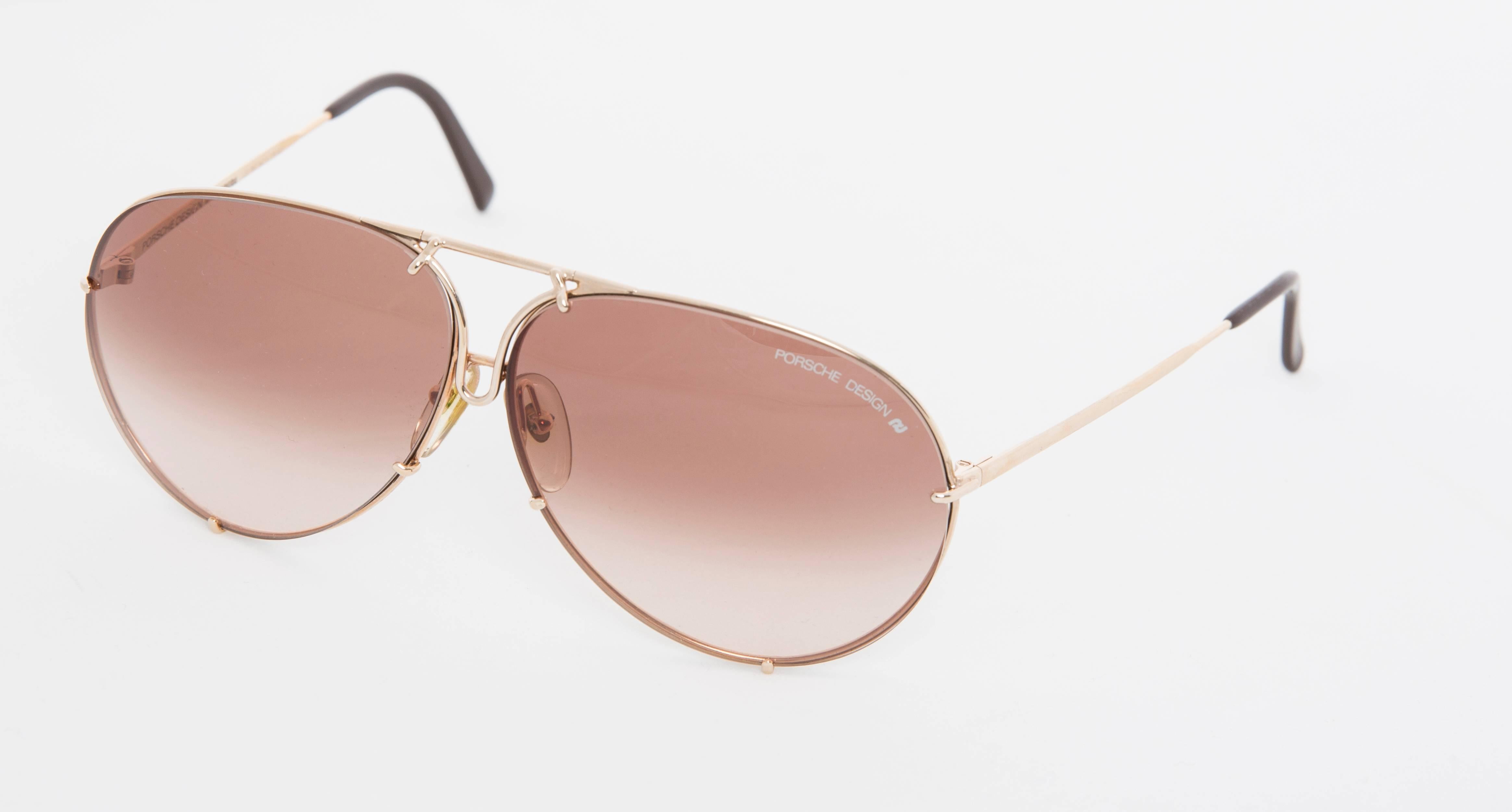 Porsche Design by Carrera model 5621, circa 1980's aviator sunglasses. The classic sunglasses are in gold toned rims, with gradient brown lens. The hard case contains the additional green lenses in a fitted compartment.

6.0
