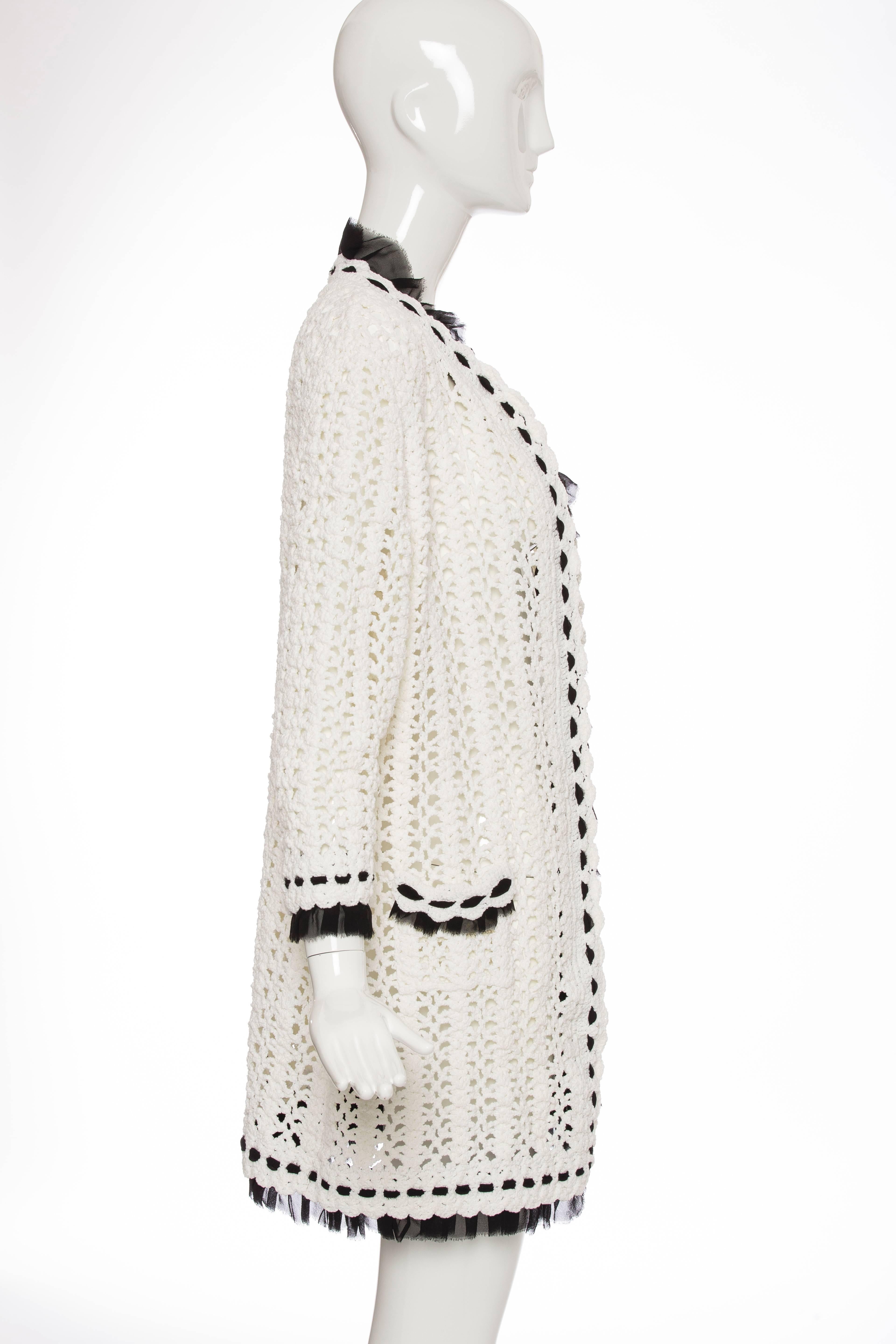 Chanel, Spring 2005, ivory long sleeve crochet knit cardigan with black silk chiffon trim throughout and dual patch pockets at front.

FR. 42
US. 10

 Bust 39”, Waist 38”, Length 31”
Fabric Content: 81% Nylon, 18% Cotton, 1% Elastane; Combo