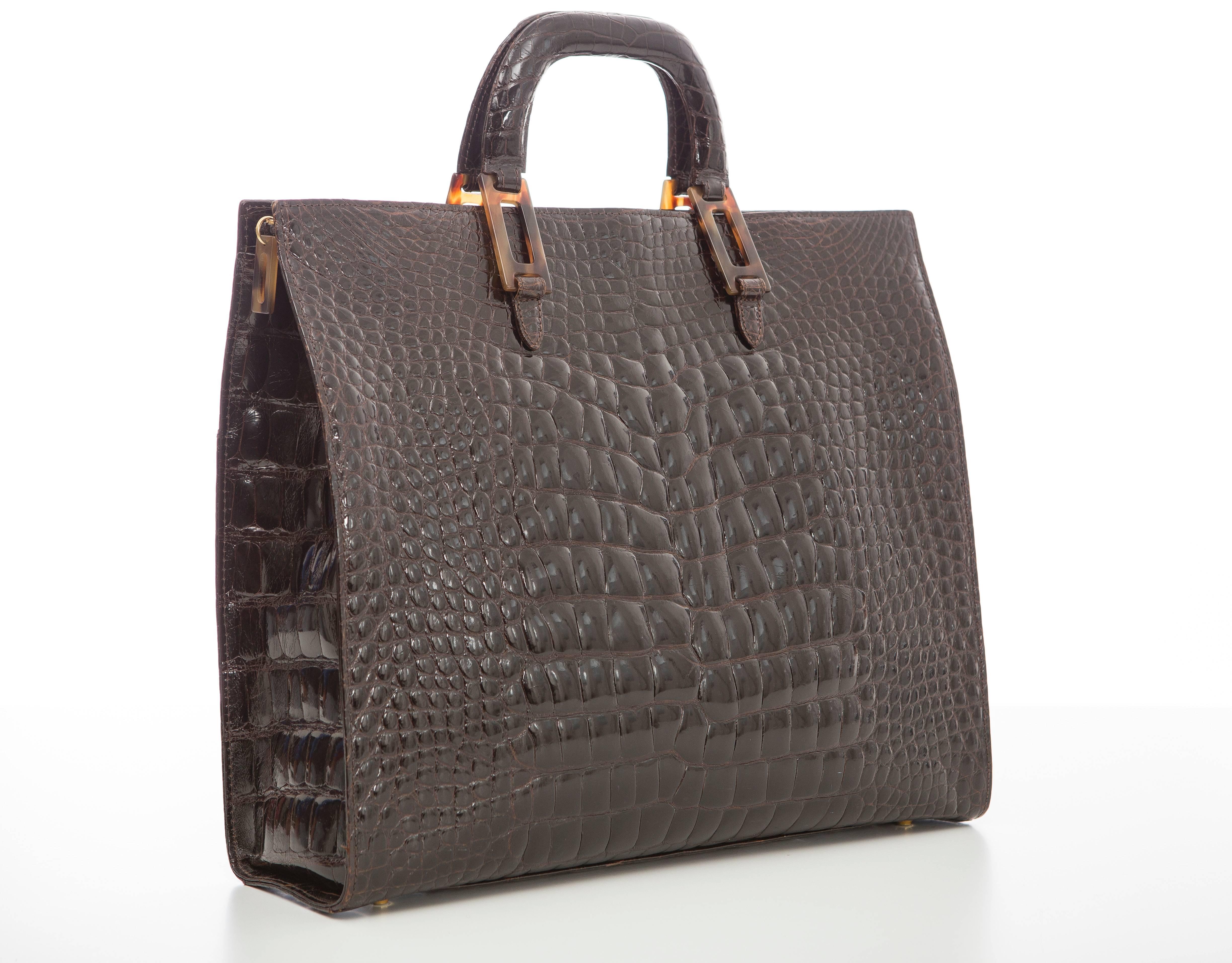  Lana Marks chocolate brown alligator tote with gold-tone hardware, dual flat top handles, black leather lining, three pockets at interior walls; one with zip closure and zip closure at top.

 Handle Drop 3”, Height 12”, Width 14”, Depth 4”