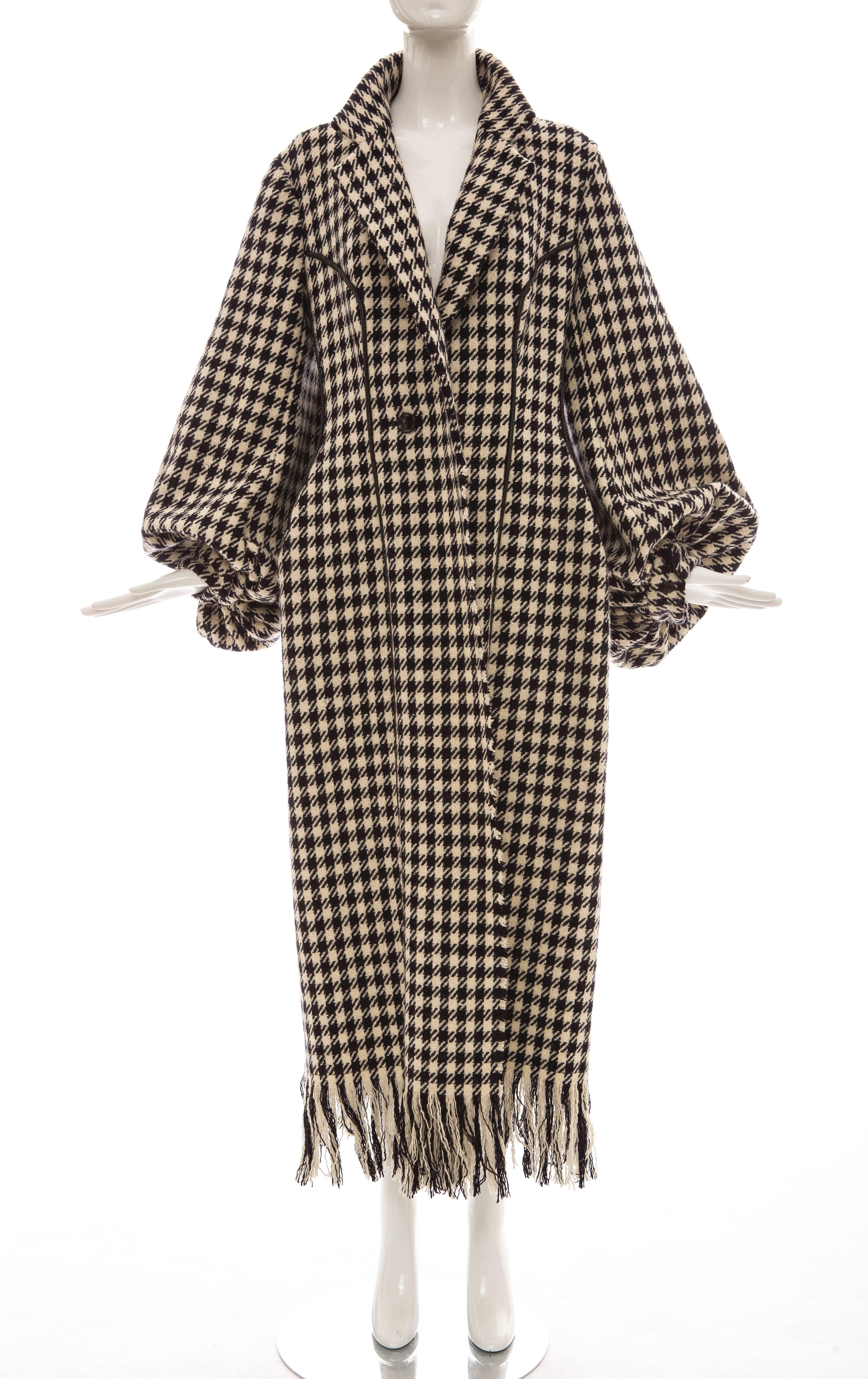 Yohji Yamamoto, Autumn-Winter 2003 black and white wool houndstooth coat featuring notched lapels, blouson sleeves, dual seam pockets, leather piping throughout, fringe trim at hem and single button closure at front.

Japan: Large

 Bust 42”,