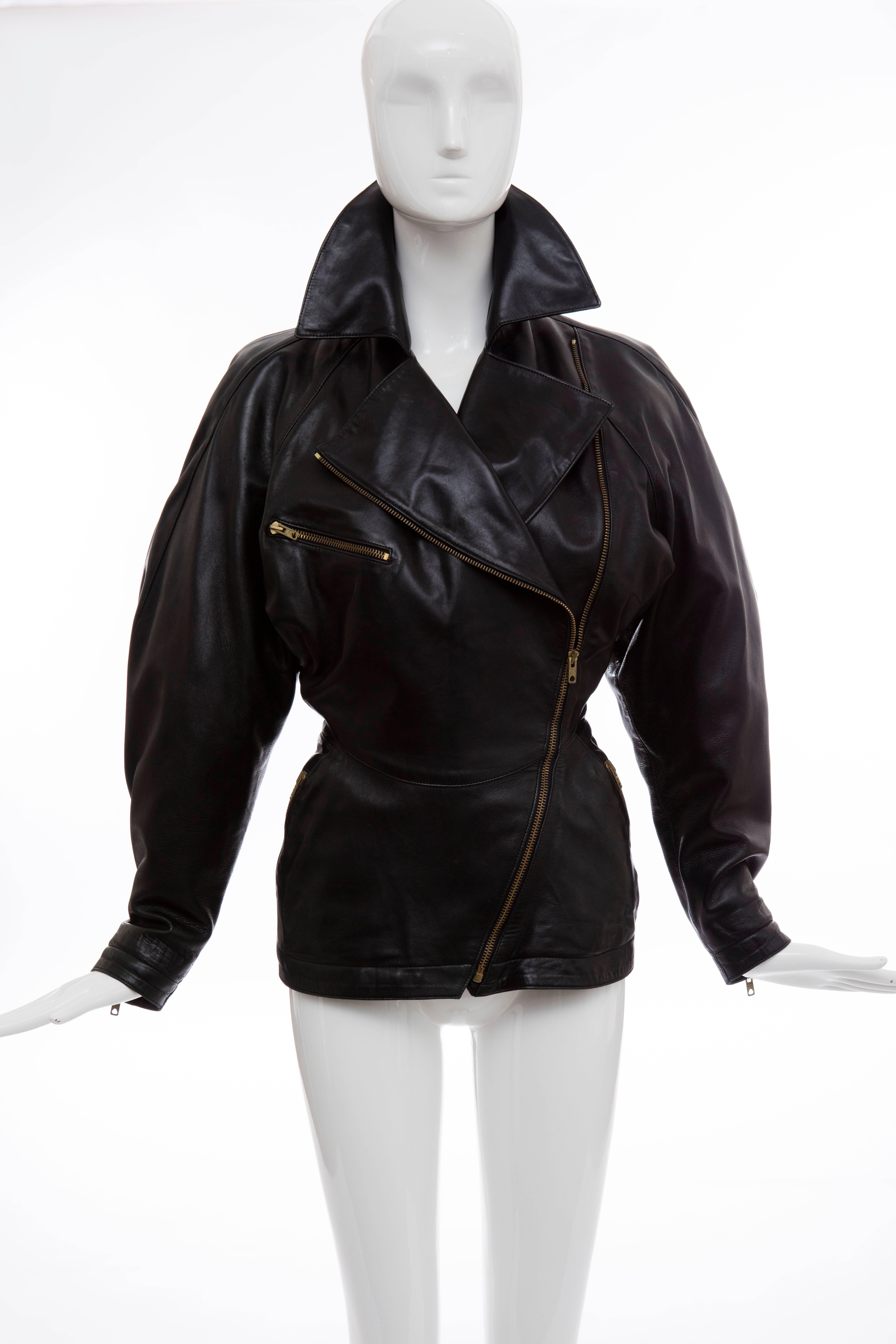 Azzedine Alai, circa 1986 black leather jacket with Eclaire zipper pulls and  hardware with zippered pockets and sleeve cuffs in an antiqued gold-tone finish, notched lapel and fully lined in black acetate with signature cloth label.
 
FR. 38
US.