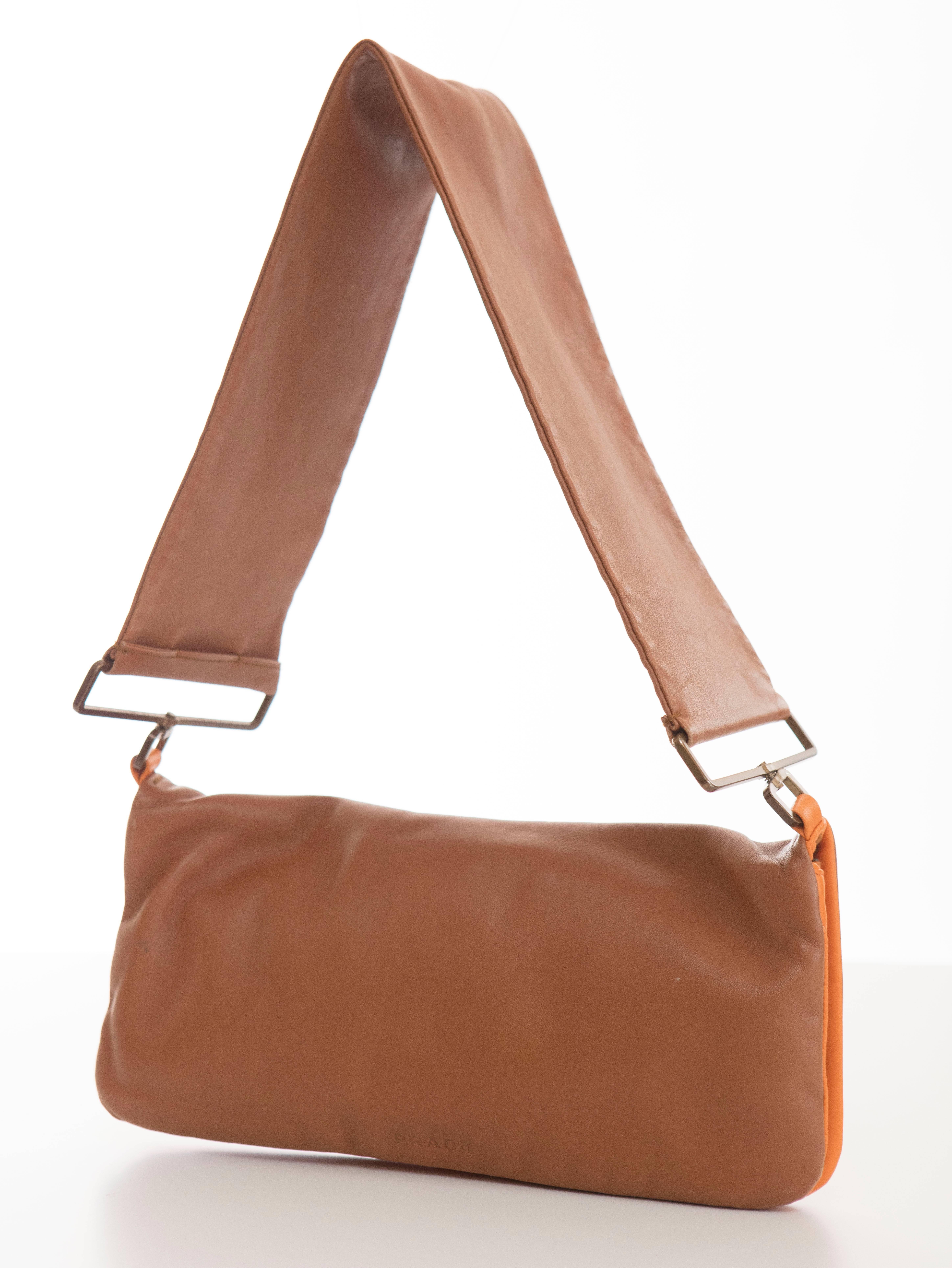 Prada snap front, cognac and tangerine leather shoulder bag with zip closure and fully lined in satin.

Width 11, Height 5.5, With Strap 15, Width of Strap 3.5, Depth .5