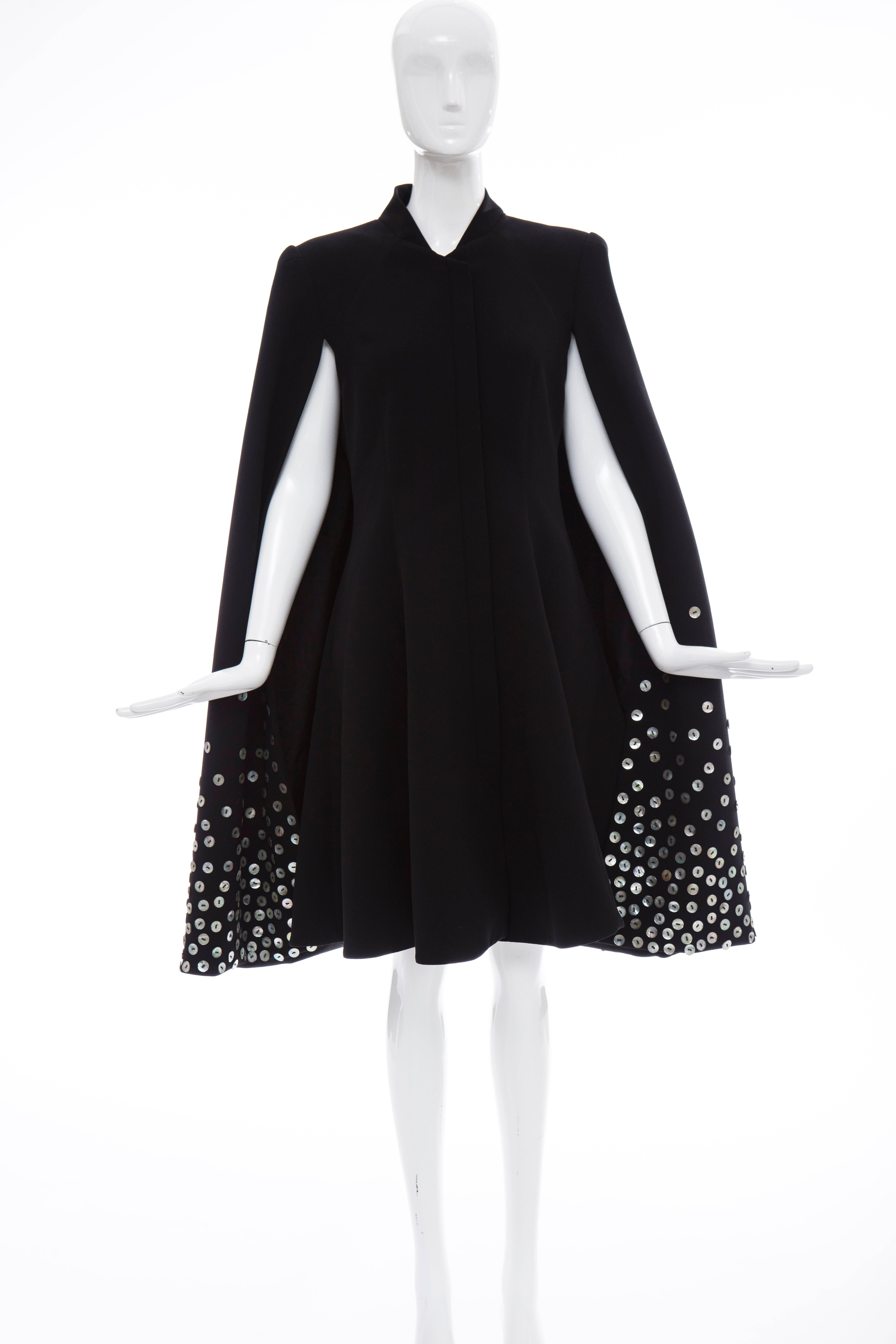 Gareth Pugh, Spring-Summer 2015 black dress with standing collar, cape overlay, mother of pearl button accents throughout, dual slit pockets at sides and concealed zip closure at front. 

GB. 12
US. 10
IT. 44

Bust: 36, Waist 32, Hip 48, Length