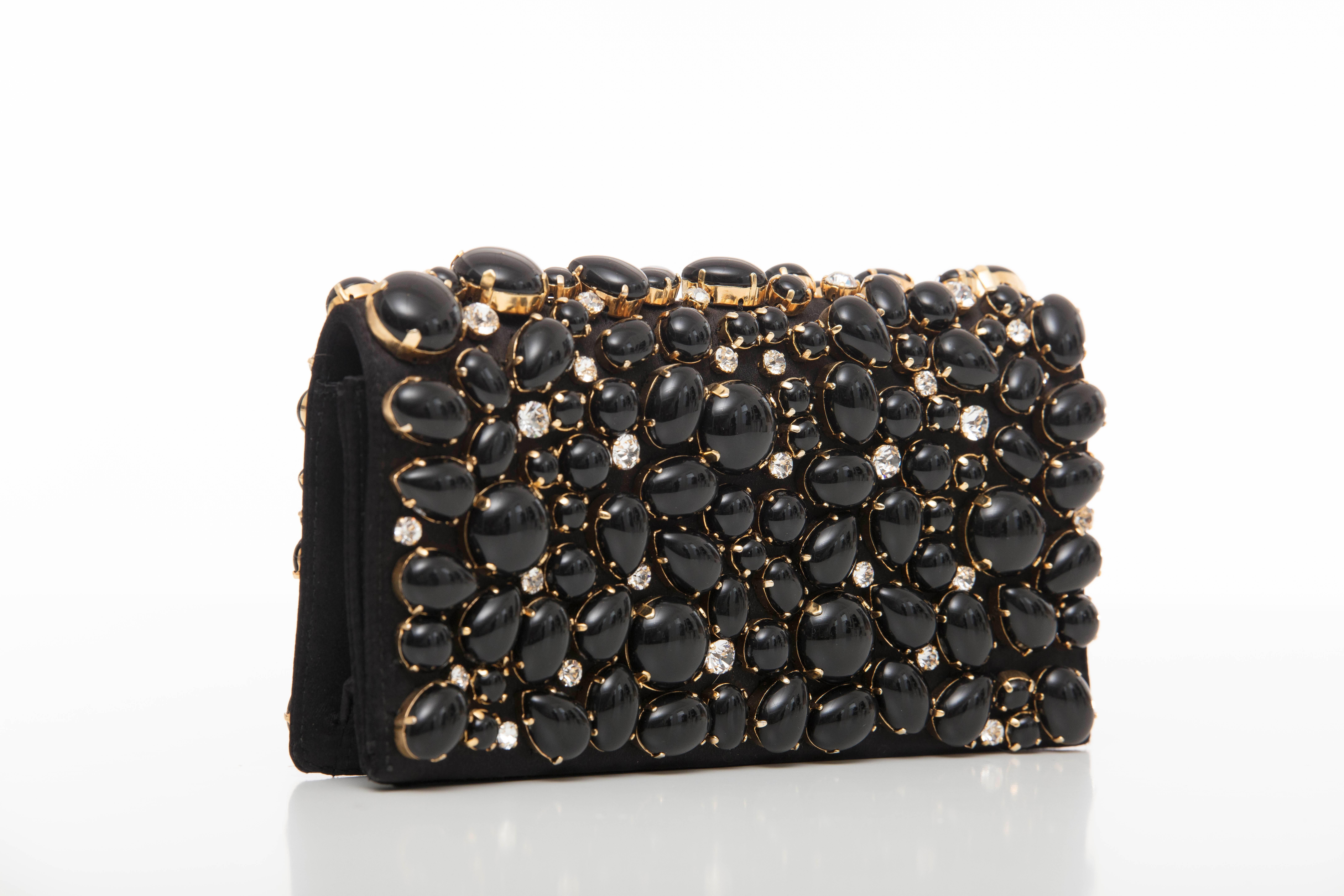 Prada, Spring-Summer 2011, black silk satin Raso Pietre evening clutch with gold-tone hardware, cabochon and prong set crystal embellishments throughout, card slot at interior and magnetic snap closure at front flap.


Height: 4.5, Width 7.5, Depth