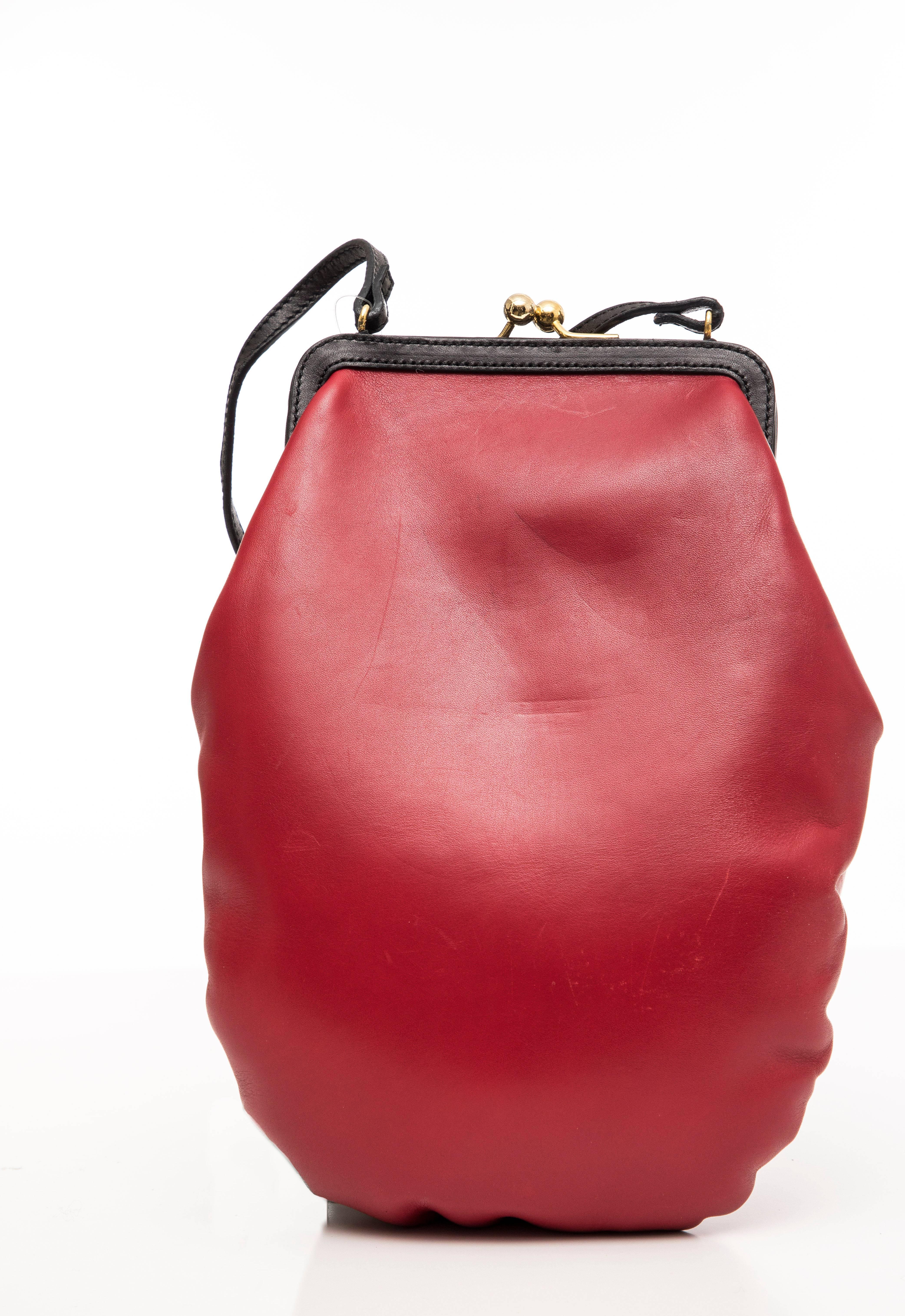 Moschino, printemps 2001, sac à main en cuir rouge et noir avec gant de boxe, ferrures métalliques dorées, bandoulière plate unique, lacet à l'extérieur, doublure en tissu noir et fermeture à baiser sur le dessus.

Hauteur 11.5, Largeur 7.5,