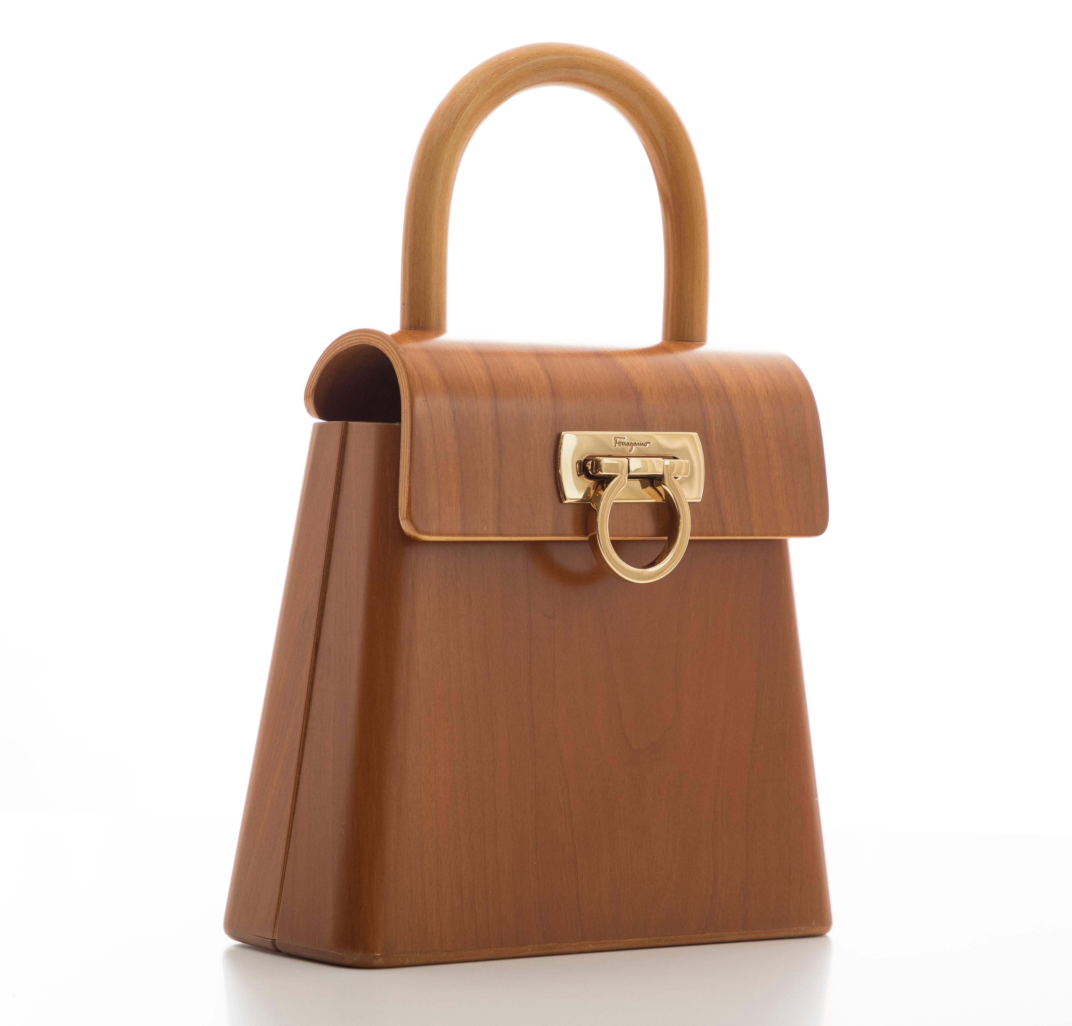 Salvatore Ferragamo, Circa: 1997-1998 top handle marrone cherry wood handbag with gold-tone gancini clasp, fold over and hinged magnetic top opening, one slot pocket and lined in black jacquard fabric. Serial Number: AU-21-7728

8.5