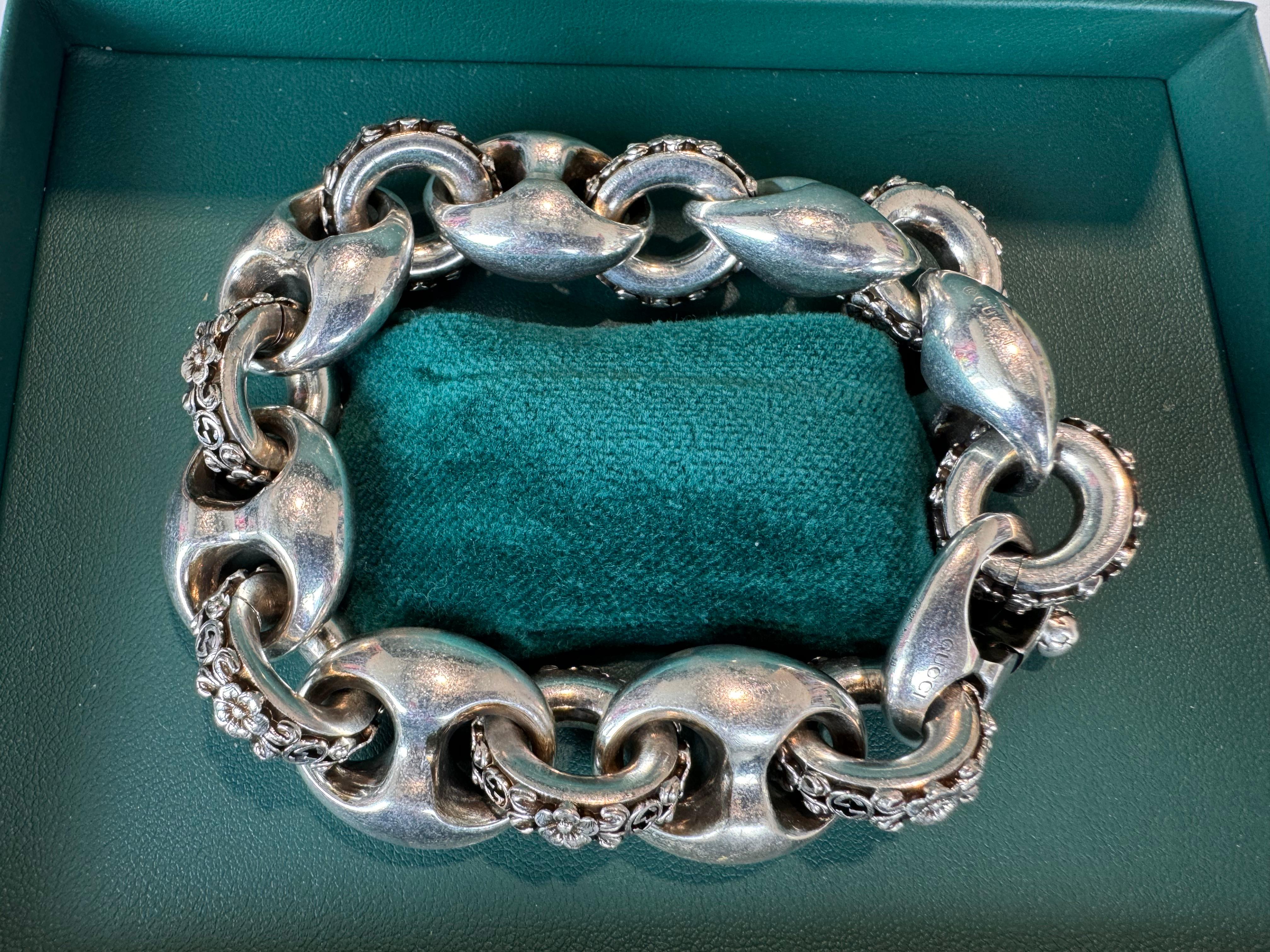 Express your individuality with this Sterling Silver Interlocking G Marina Chain Bracelet from Gucci. Adorned with a three-dimensional flower motif, this bracelet has a vintage look that will add a unique touch to your style. It is 21cm in length