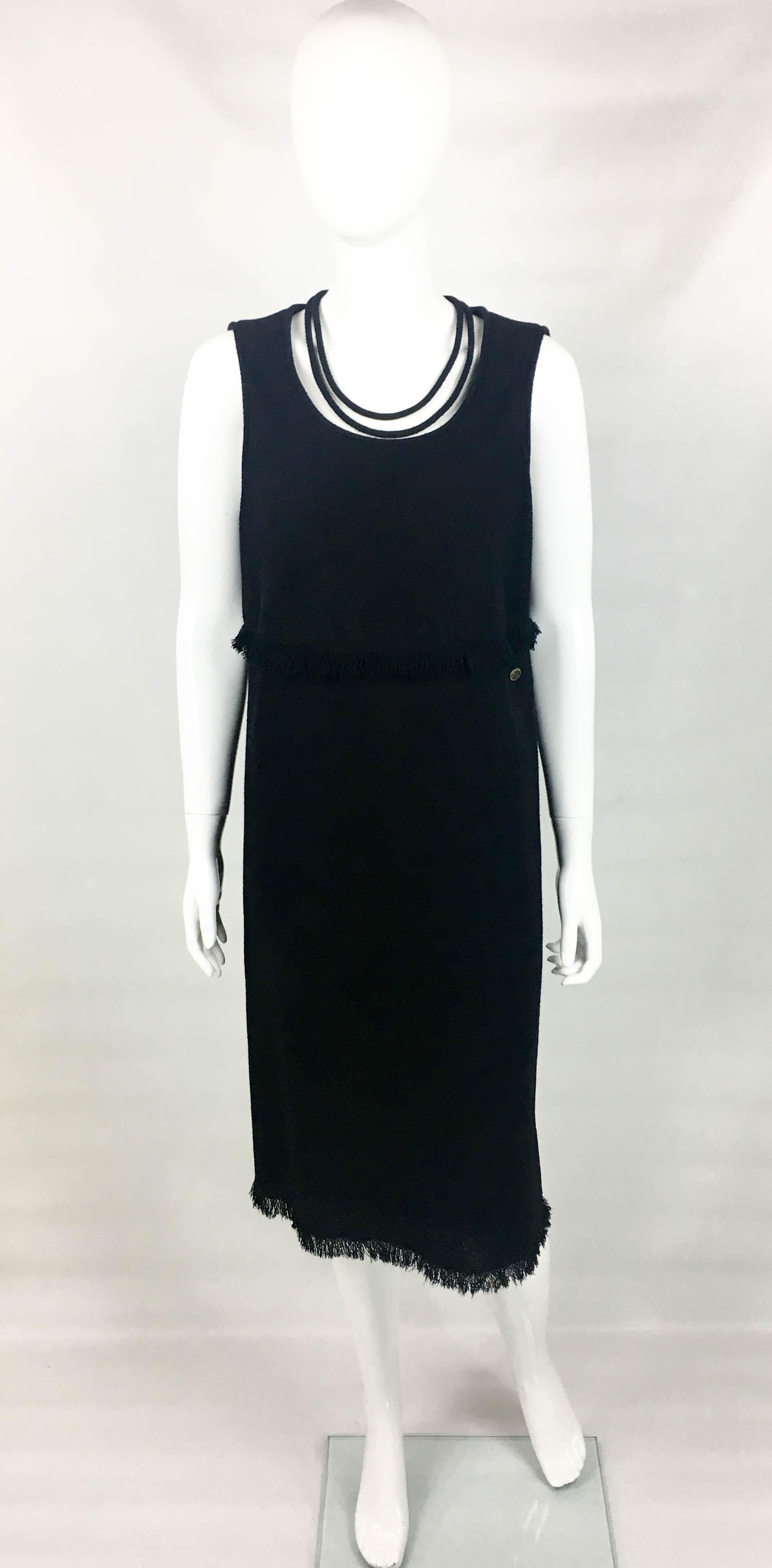 Chanel Black Wool Dress With fringing detail. This beautiful Chanel sleeveless dress is timeless piece. Made in wool, it features fringing to the waist and hem, as well as a cord detail to the neckline. It is midi in length and straight cut. Silk