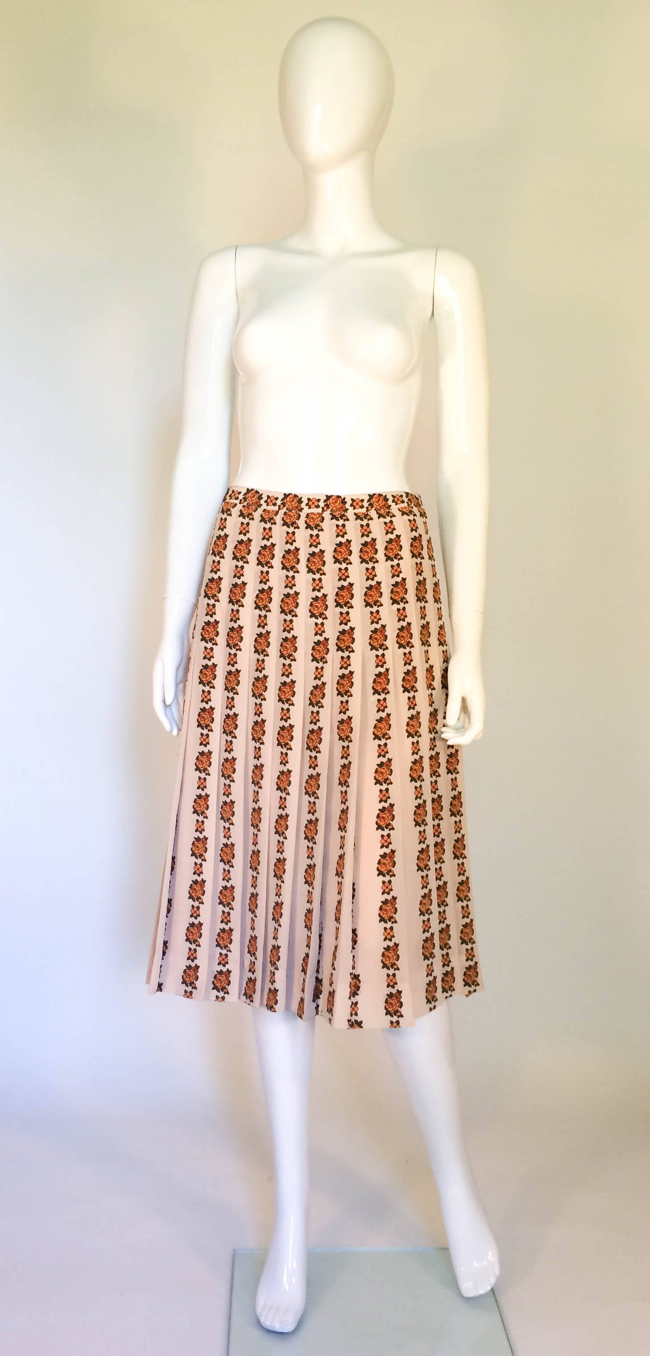 Wonderful Vintage Celine Silk Floral Skirt. Silk pleated skirt featuring a high rise, a waistband, a rear zip fastening, a mid-length and a flower stripe print. The colour of the skirt is beige, with orange flowers and green leaves. Fully lined.