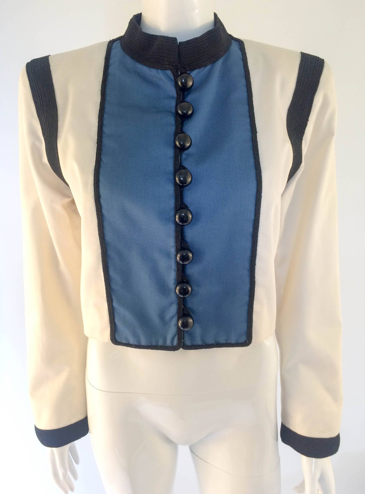 Iconic Yves Saint Lauren Rive Gauche Jacket. Bell boy inspired jacket, with front panelling and embellished with black cord-like trimmings on the collar, some of the hem and cuffs. In ivory and blue. Shoulder pads. Fully lined. This is a timeless