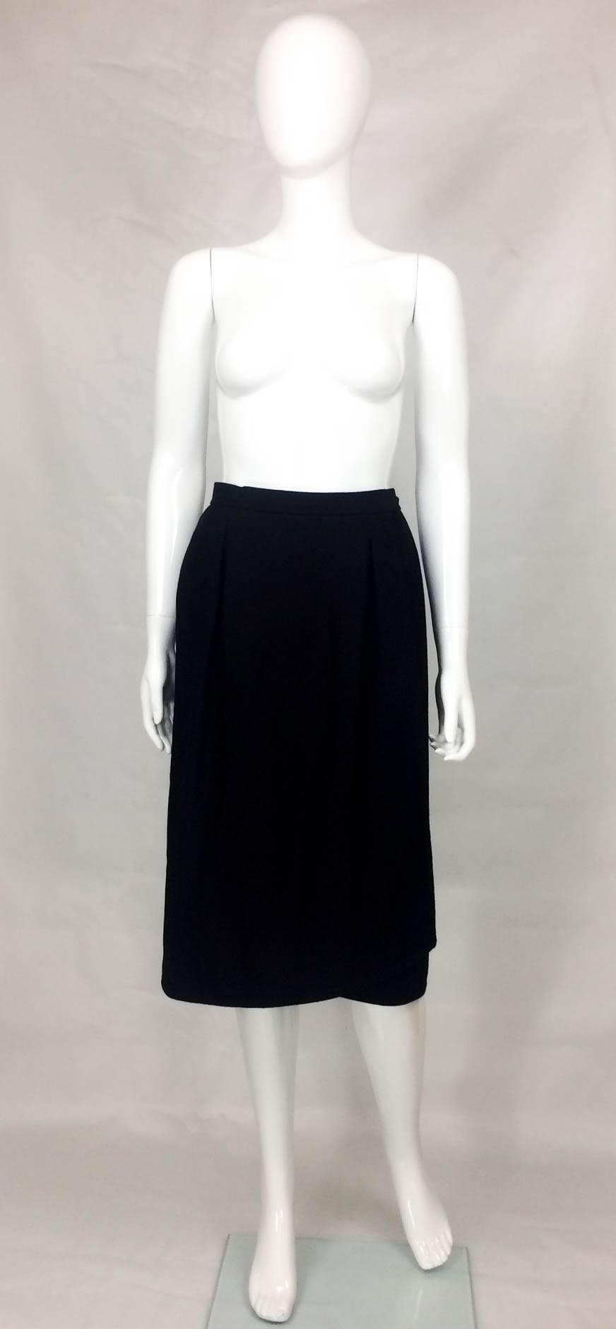 Very Smart Yves Saint Laurent Wool Skirt. This chic wrap skirt is made in the very soft black wool. It features 2 side-pockets. Midi in length, this skirt is fully lined. This is an extremely versatile and elegant piece.

Designer/Label: Yves