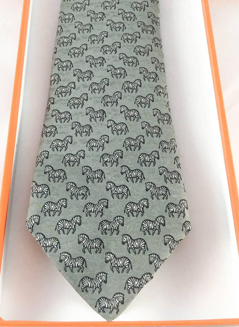 Stylish Hermes Silk Tie. Made in pure silk, this numbered print (7110 OA) in grey features zebras. This is a classy way to some fun to a suit. A quirky and elegant bit of fashion. In the original box.

Label/Designer: Hermes
Period: 21st