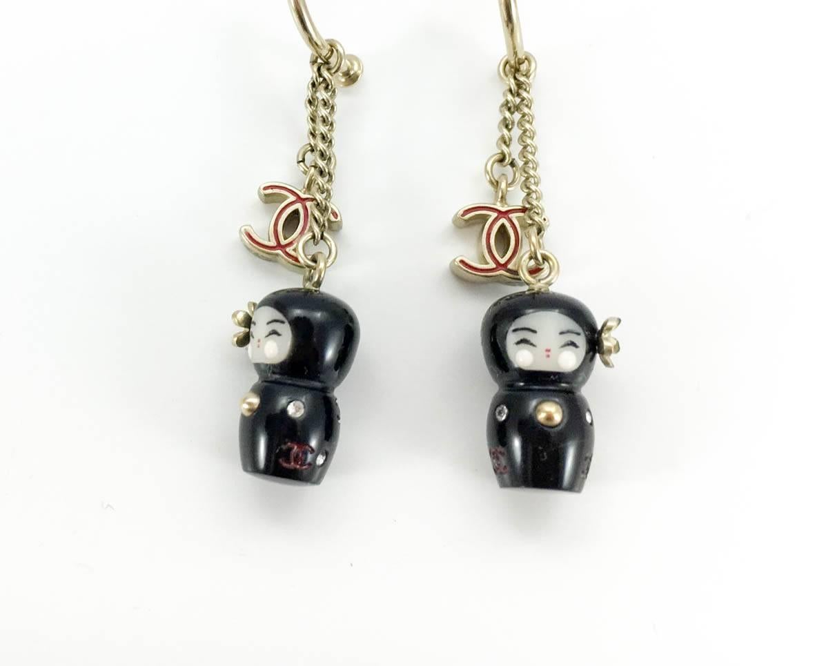Amazing Chanel Chinese Doll Earrings. These fabulous Chanel earrings are from the highly desirable and coveted Paris-Shanghai Collection, 2010. They are comprised of a half hoop with 2 chains hanging from it; one with the iconic red Chanel logo at