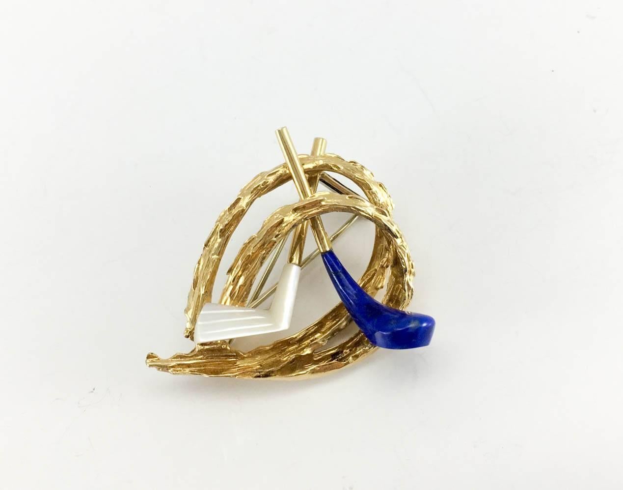 Exquisite Vintage Chaumet Golfing Brooch. This beautiful piece of jewellery by Chaumet dates back from the 1960s. Crafted in 18K gold, it consists of an organic design with two golf clubs in the centre, one with a lapis lazuli end and the other with