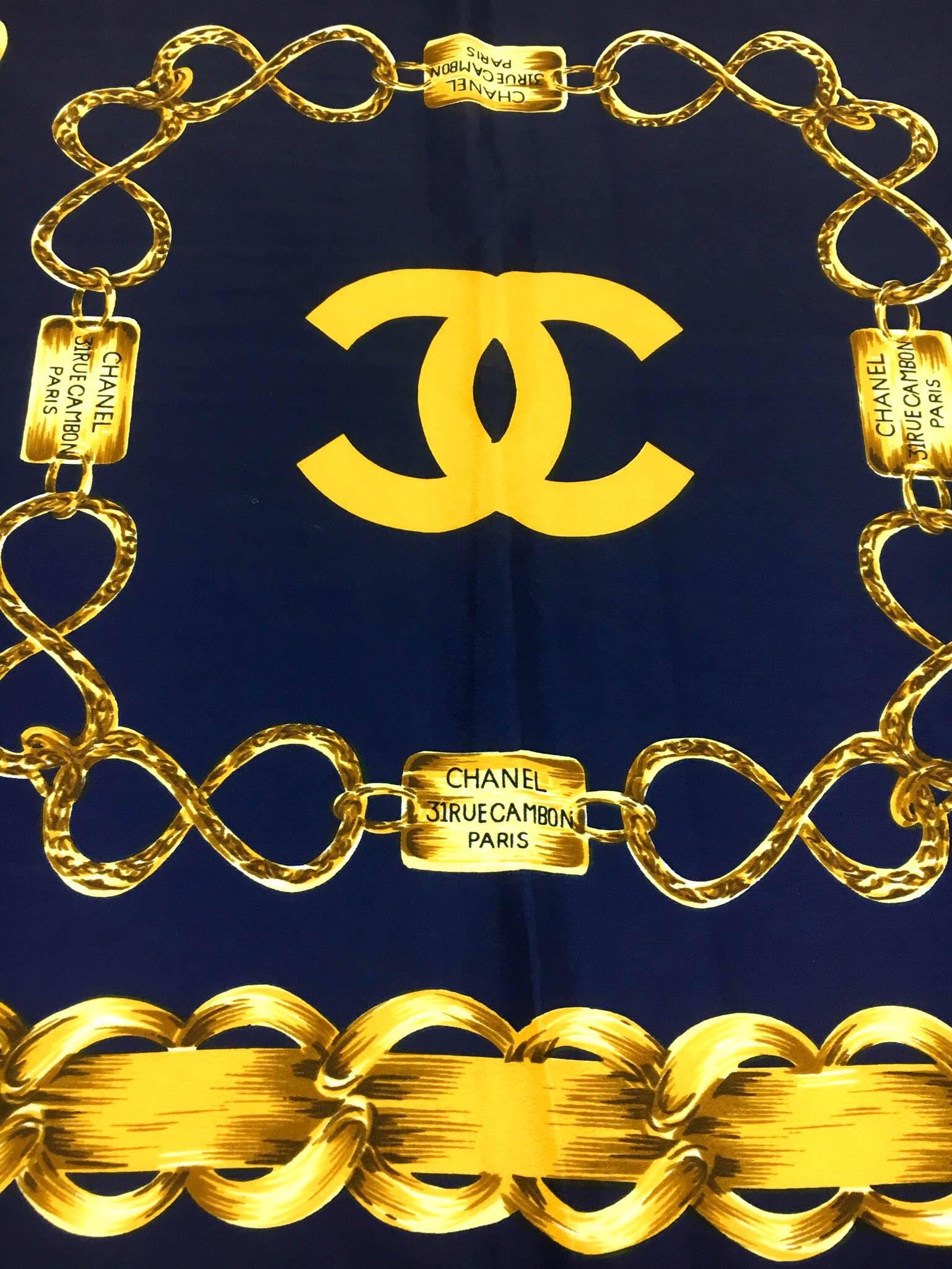 Gorgeous Vintage Chanel Scarf. This beautiful Chanel scarf is made in pure silk and dates back from the 1990s. In navy blue and golden, it features various designs of chains (an ever recurring motif at Chanel), 4 medallions, 8 plaques saying Chanel,