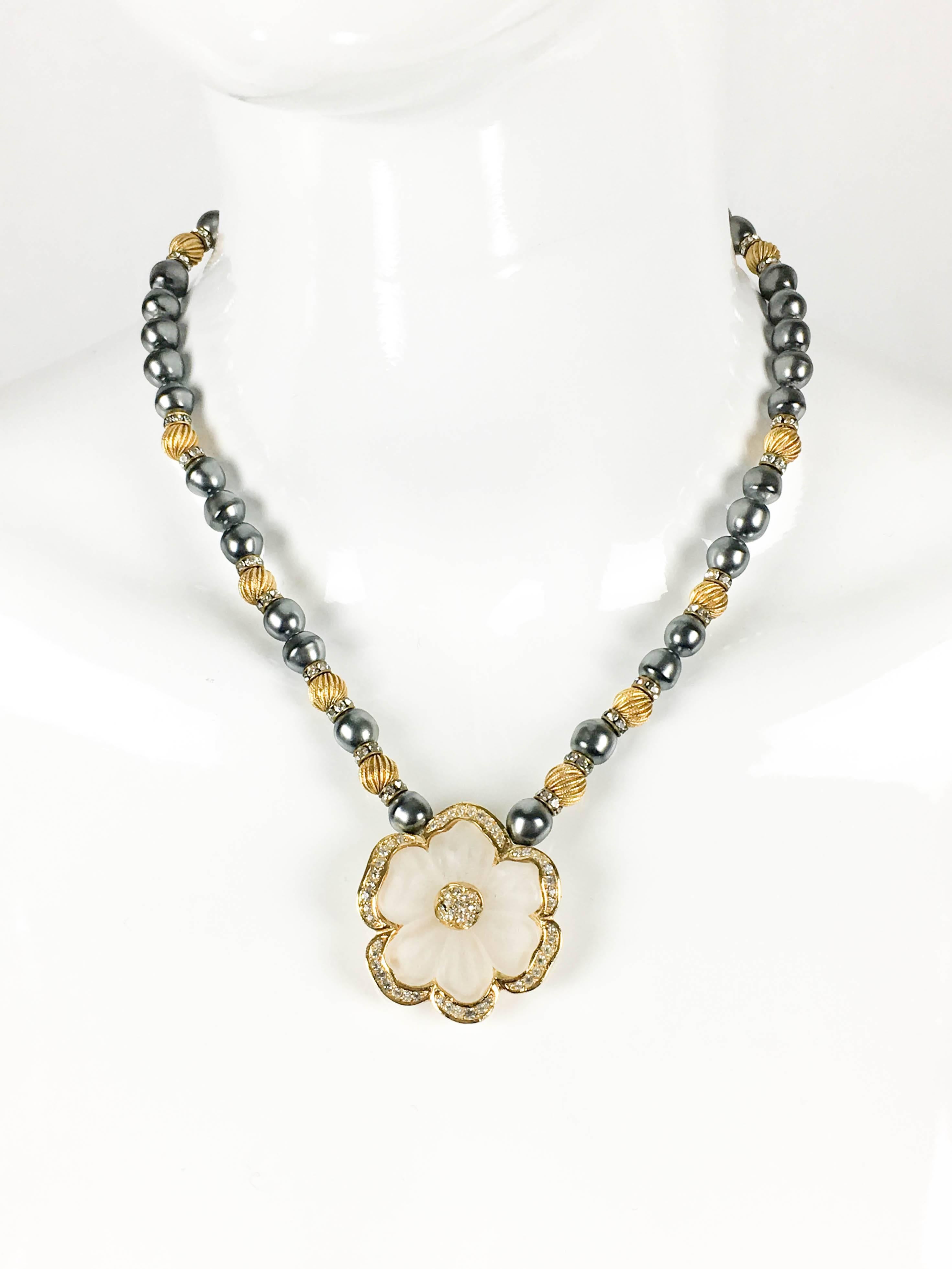 Beautiful Dior Vintage Flower Necklace. This stylish piece by Dior dates back from the 1990’s. It features grey faux pearls, textured golden beads, spaced by paste/rhinestone embellished rings. The main aspect of this necklace is the flower pendant