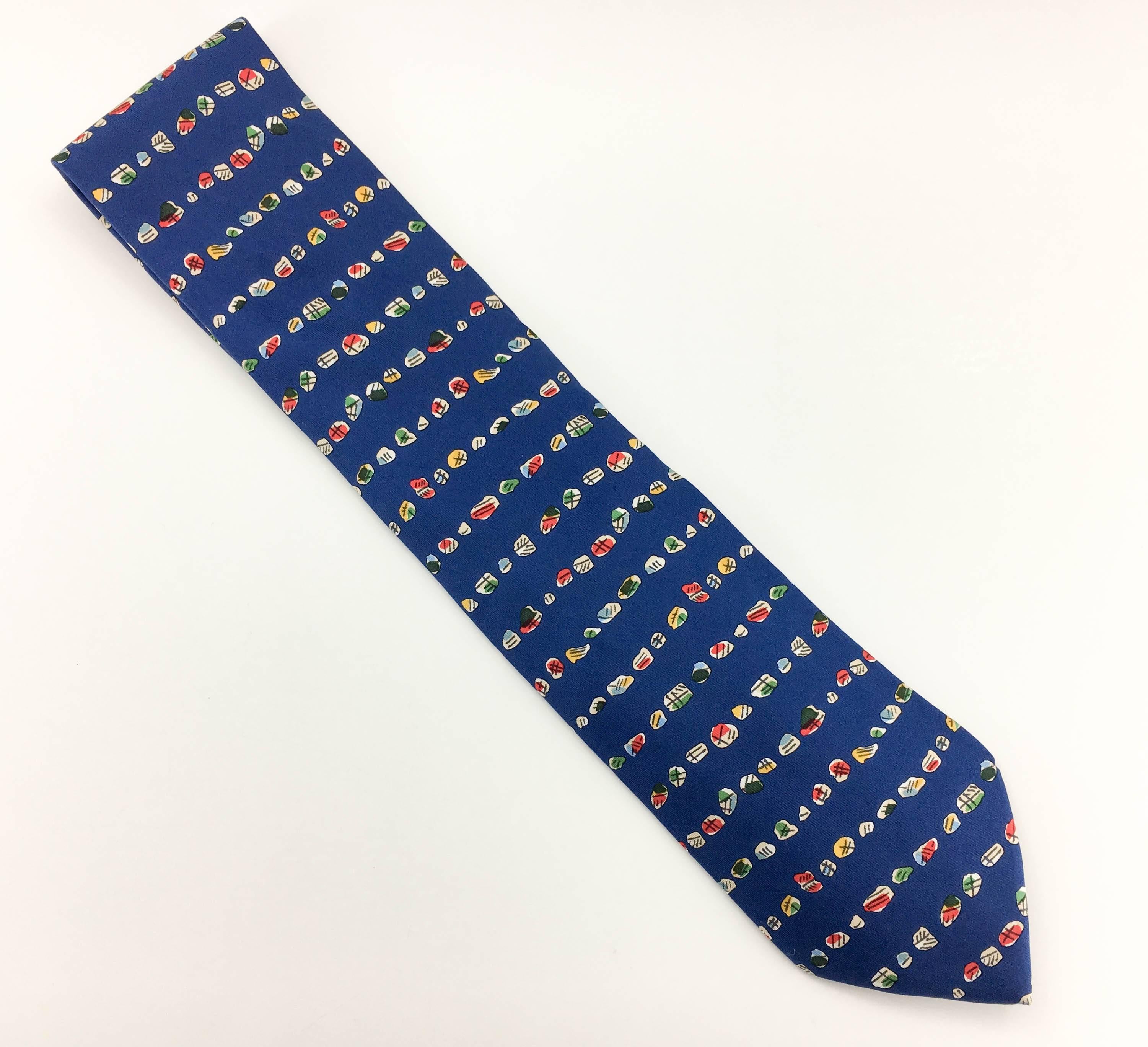Stylish Hermes Silk Tie. Made in pure silk, this numbered print (7832 UA) on a blue background features various abstract designs. This is a classy way to some fun to a suit. 

Label/Designer: Hermes
Period: 21st Century
Origin: France
Material: