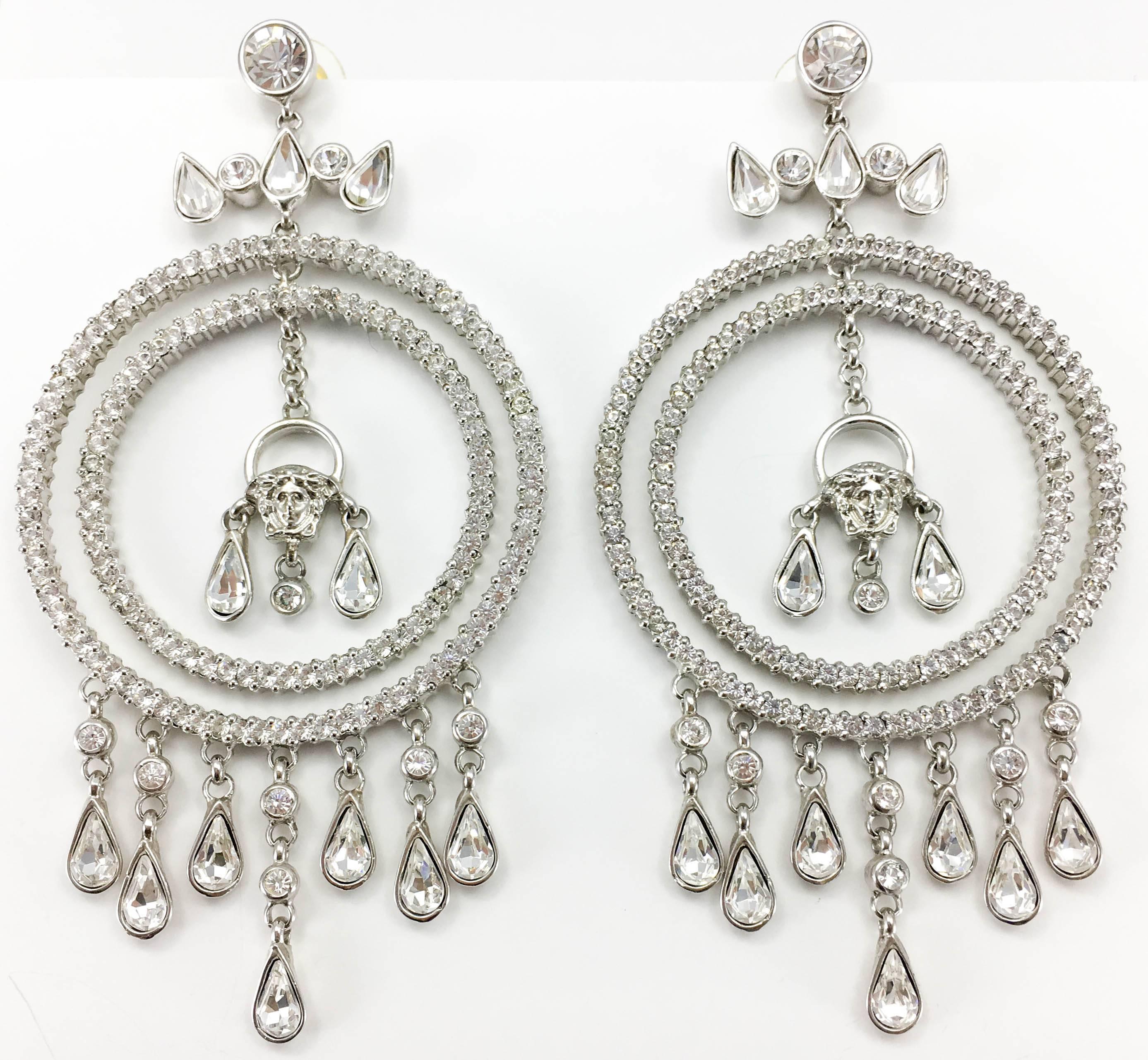 Fabulous Versace Chandelier Earrings. These amazing earrings by Versace are truly show-stoppers. In white metal, they feature 2 diamanté encrusted hoops, various dangling teardrop-shaped crystals and Versace’s trademark, the iconic ‘Medusa’s Head’