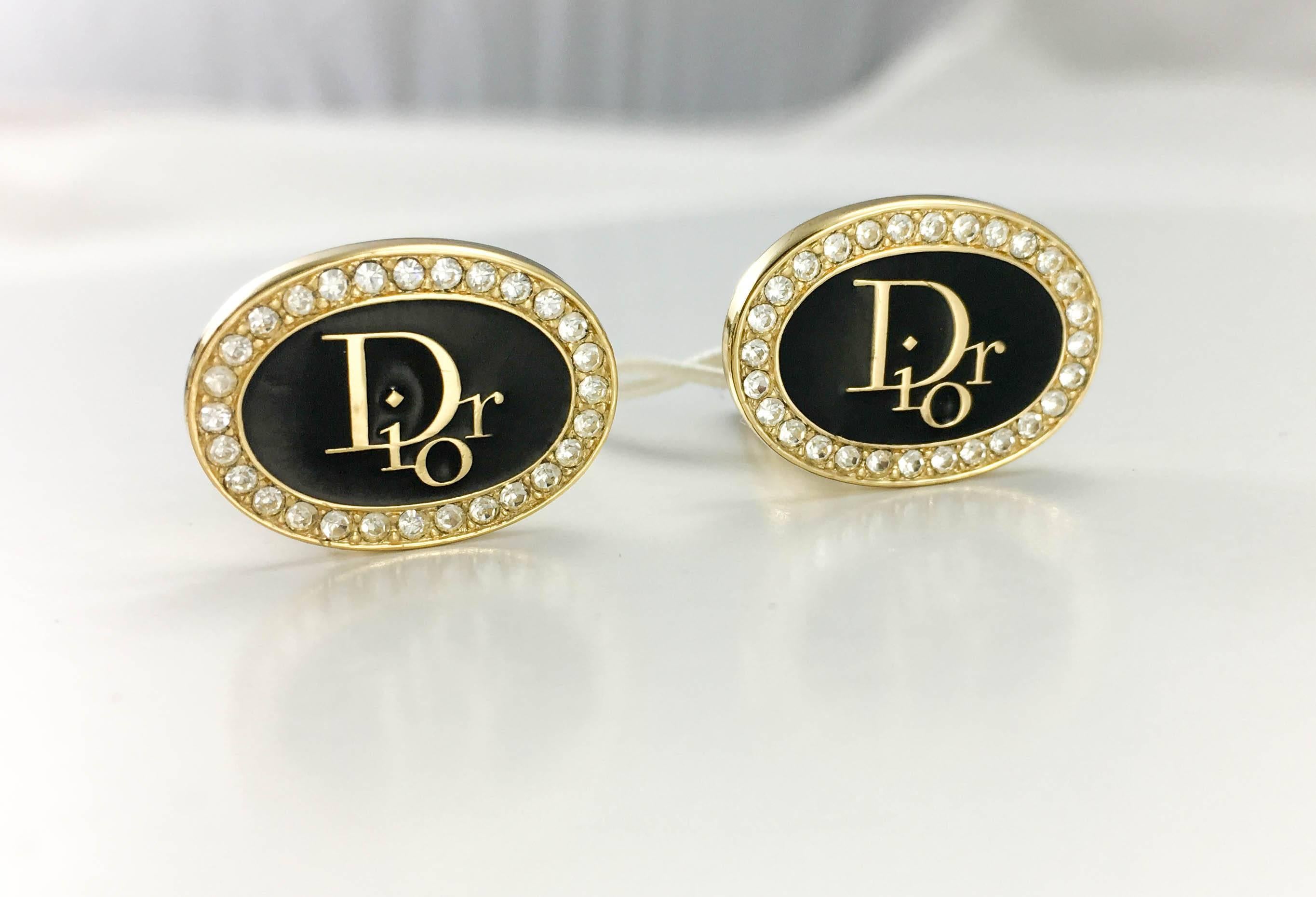 Stylish Vintage Dior Insignia Cufflinks. These beautiful cufflinks by Christian Dior date back from the 1980’s. The oval design features a black enamelled centre saying ‘Dior’ in gold-tone letters and a rhinestone/paste embellished rim, the hardware